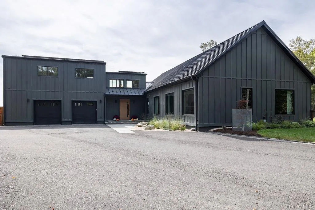 View of front of house with board and batten siding, a standing seam roof, a garage, a metal roof, and driveway View of front of house with board and batten siding, a standing seam roof, a garage, a metal roof, and driveway