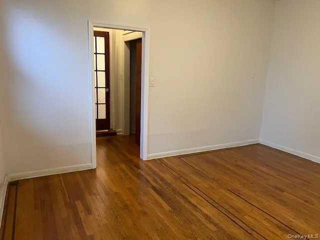 Spare room featuring dark wood-type flooring and baseboards Spare room featuring dark wood-type flooring and baseboards