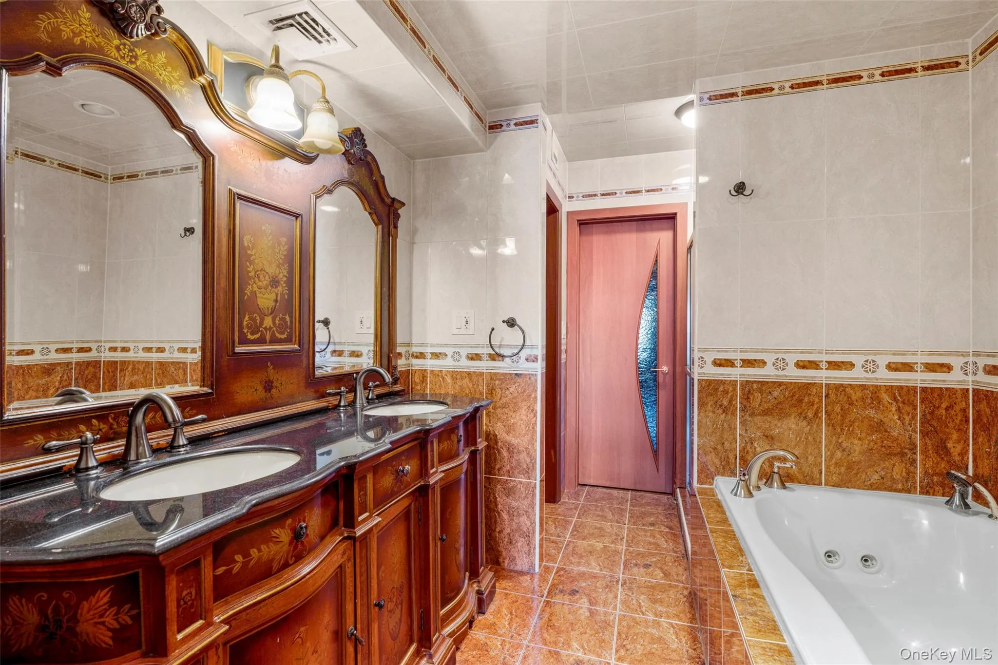 Full bathroom with a tub with jets, double vanity, tile walls, and light tile patterned flooring Full bathroom with a tub with jets, double vanity, tile walls, and light tile patterned flooring