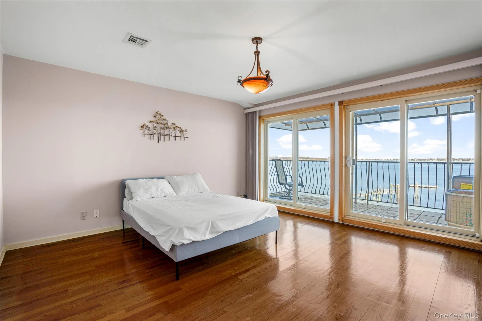 Bedroom featuring wood finished floors, access to exterior, and a water view Bedroom featuring wood finished floors, access to exterior, and a water view