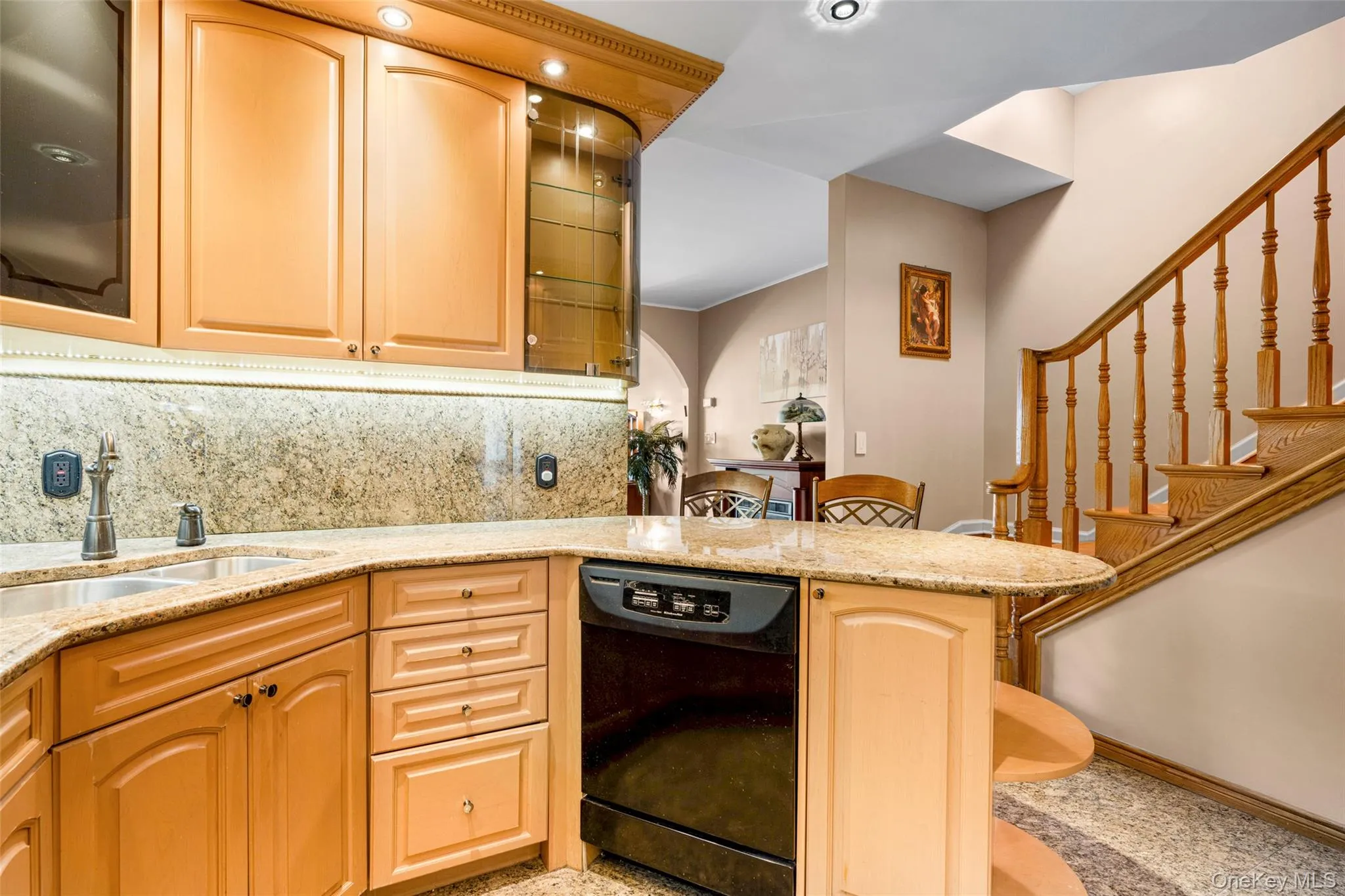 Kitchen featuring light stone counters, tasteful backsplash, a peninsula, a breakfast bar, and black dishwasher Kitchen featuring light stone counters, tasteful backsplash, a peninsula, a breakfast bar, and black dishwasher