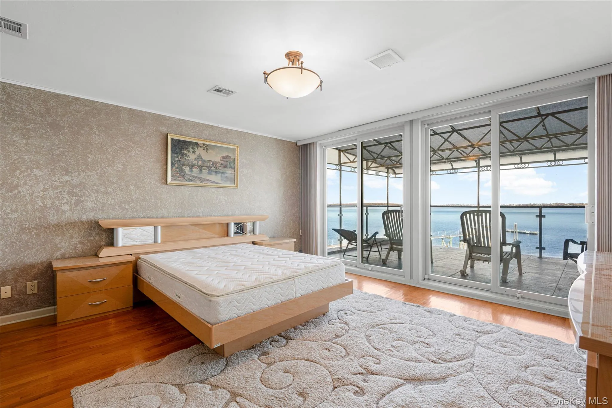 Bedroom with a water view, light wood-style flooring, a wall of windows, and access to outside Bedroom with a water view, light wood-style flooring, a wall of windows, and access to outside