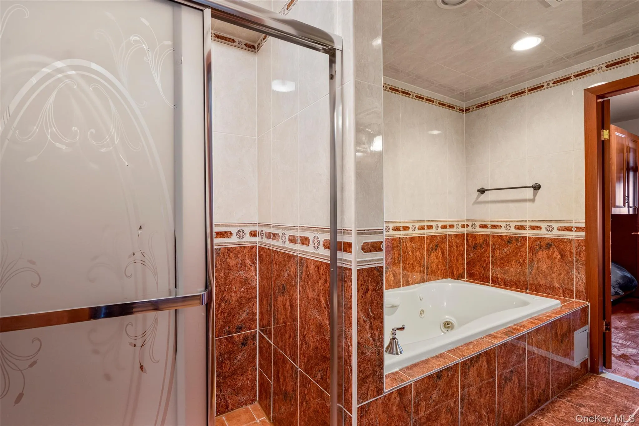 Bathroom with a tub with jets, ensuite bath, recessed lighting, a tile shower, and tile walls Bathroom with a tub with jets, ensuite bath, recessed lighting, a tile shower, and tile walls