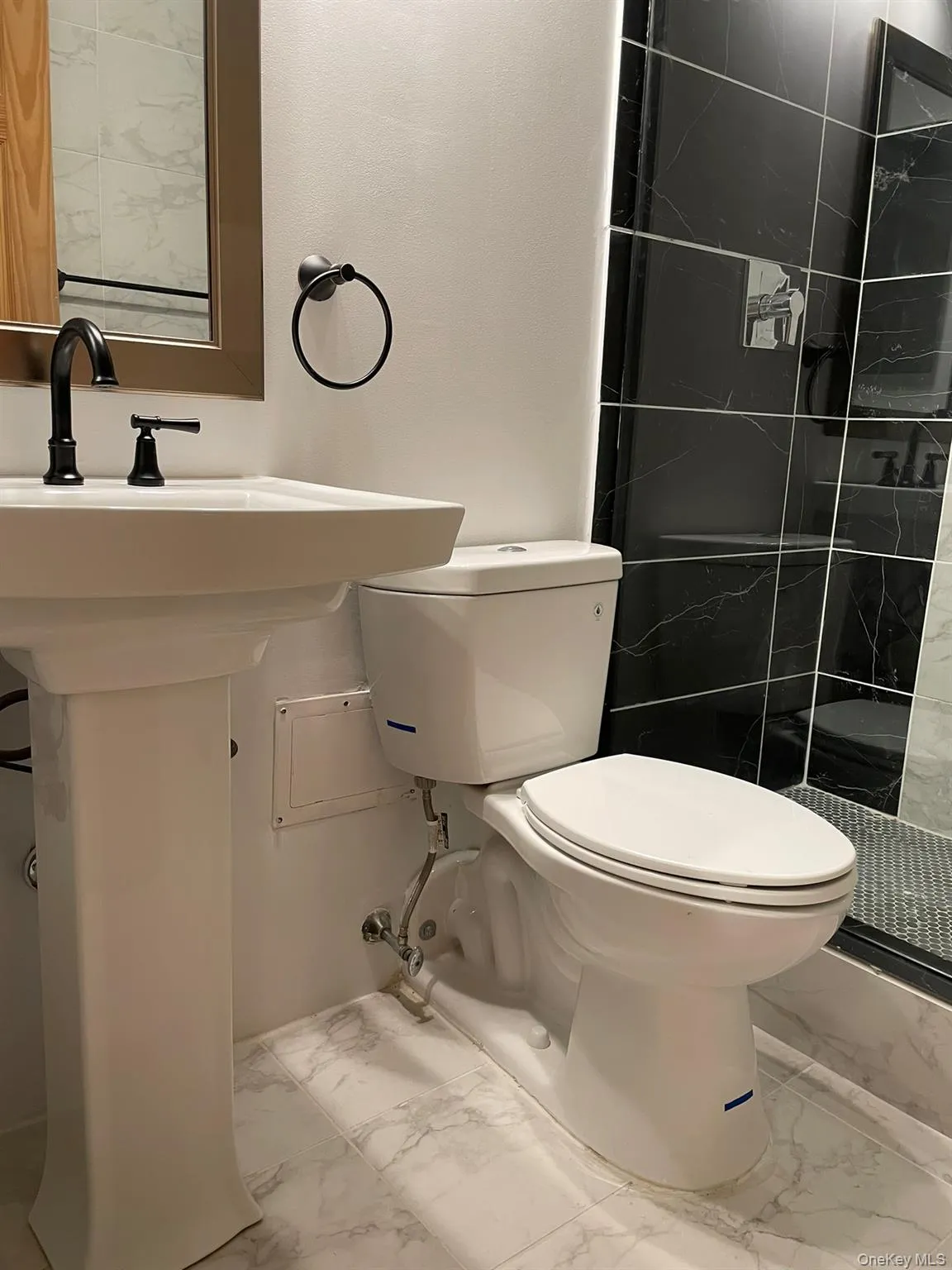 Bathroom with toilet, tiled shower, and marble finish floor Bathroom with toilet, tiled shower, and marble finish floor