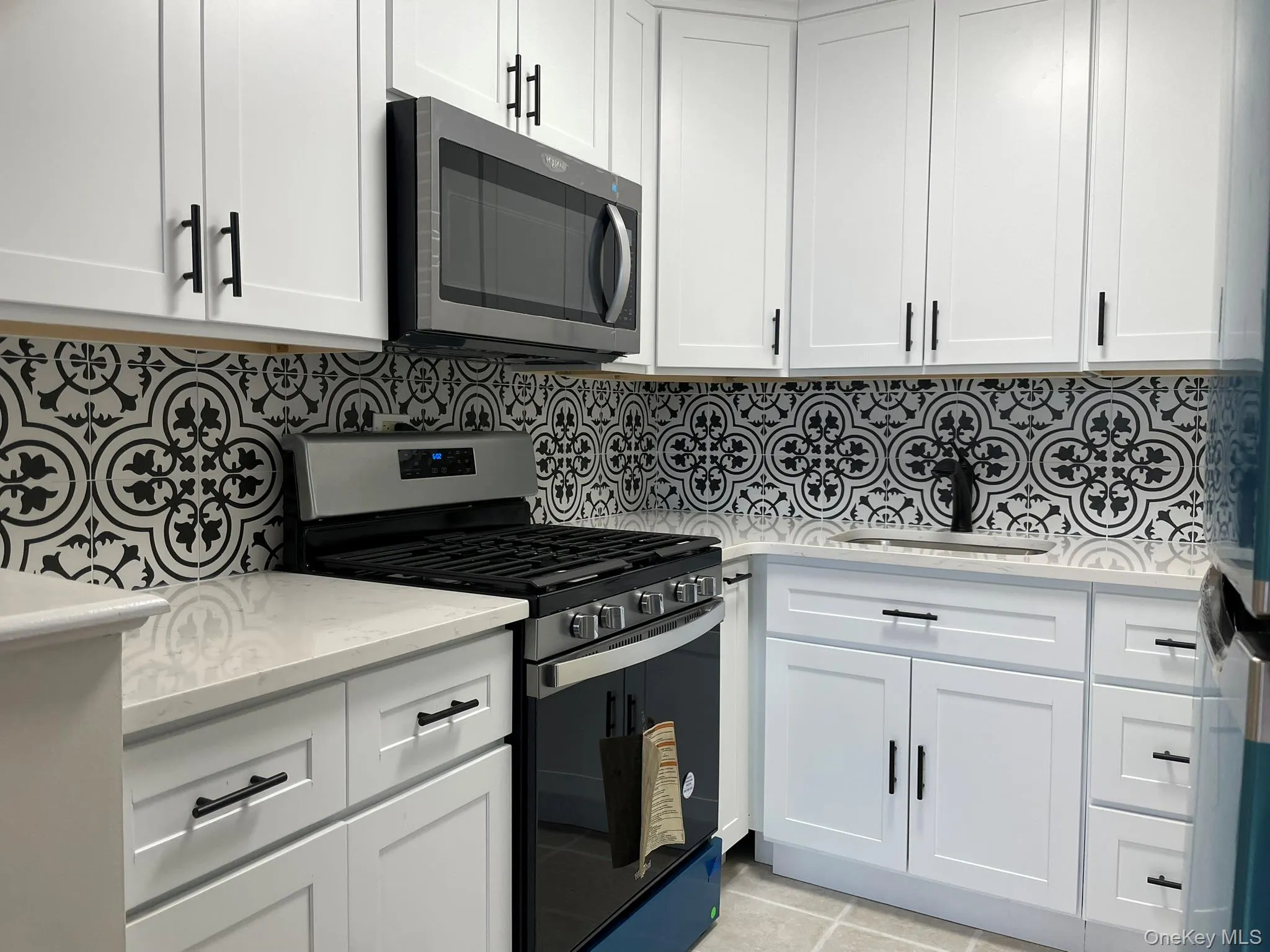 Kitchen featuring appliances with stainless steel finishes, a sink, and white cabinetry Kitchen featuring appliances with stainless steel finishes, a sink, and white cabinetry
