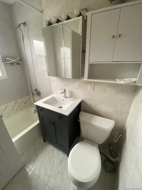 Full bath with vanity, tile walls, tub / shower combination, and tasteful backsplash Full bath with vanity, tile walls, tub / shower combination, and tasteful backsplash