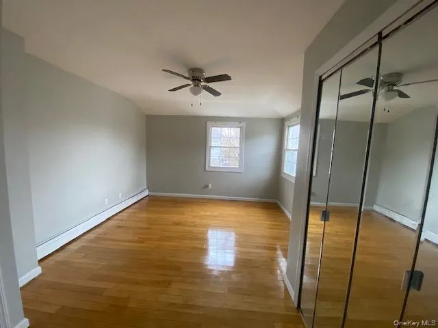 Unfurnished bedroom with a baseboard heating unit, light wood-style flooring, a closet, and a ceiling fan Unfurnished bedroom with a baseboard heating unit, light wood-style flooring, a closet, and a ceiling fan