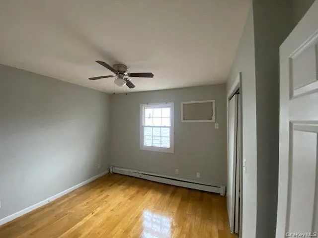Unfurnished bedroom with baseboard heating, light wood-style floors, and a ceiling fan Unfurnished bedroom with baseboard heating, light wood-style floors, and a ceiling fan