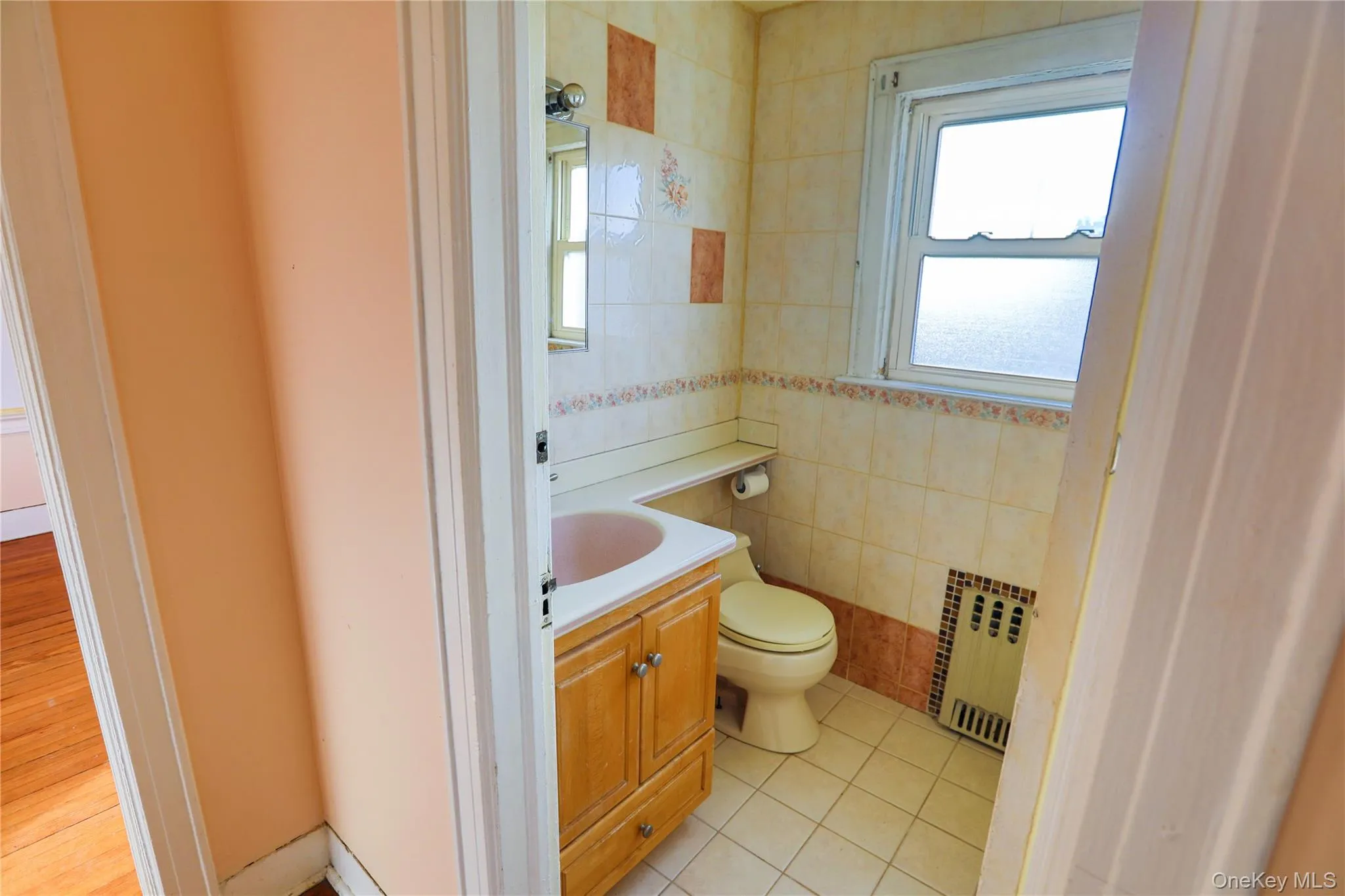 Half bathroom featuring vanity, radiator, light tile patterned floors, and tile walls Half bathroom featuring vanity, radiator, light tile patterned floors, and tile walls