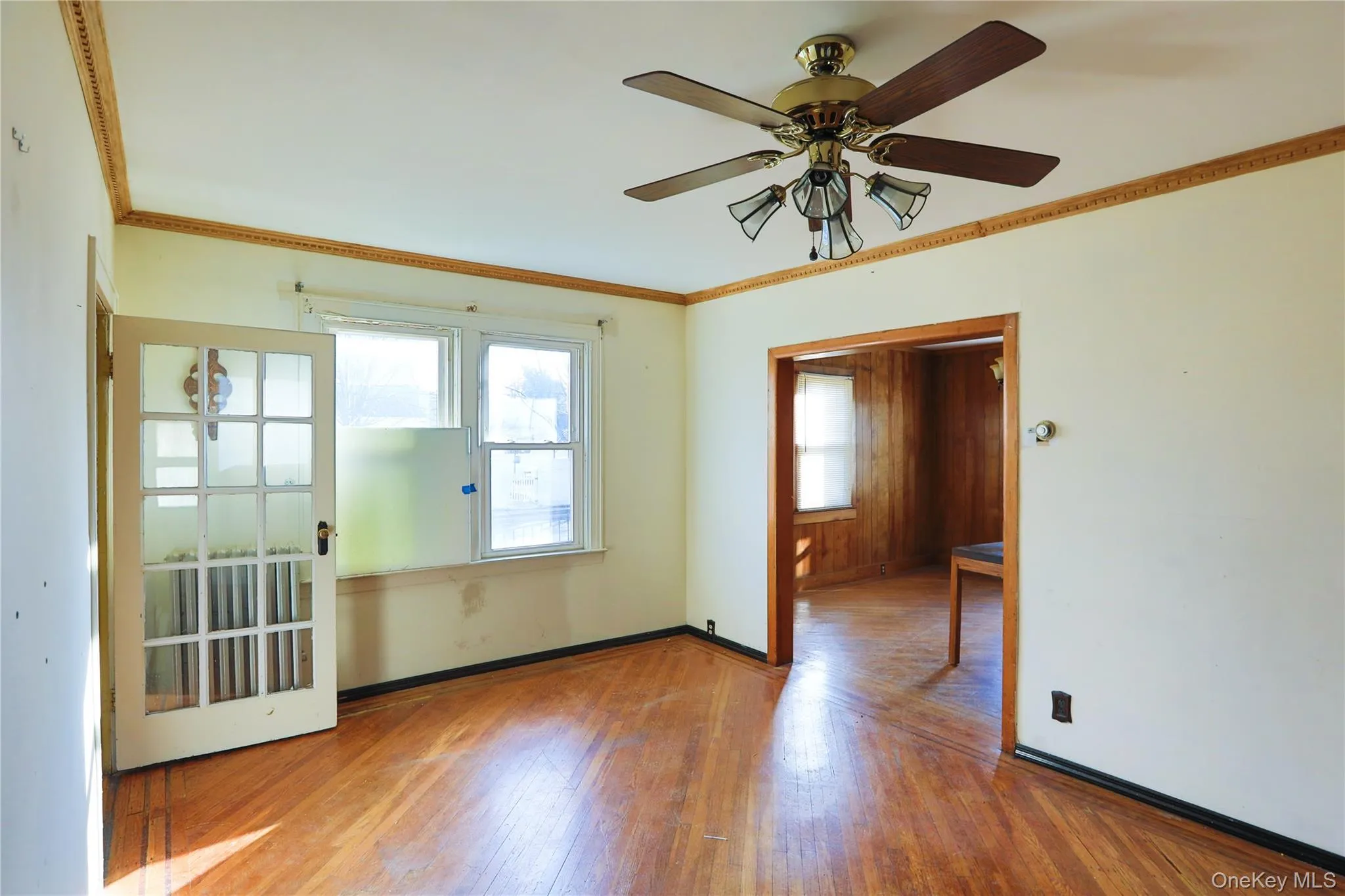 Unfurnished room featuring ornamental molding, wood-type flooring, and a ceiling fan Unfurnished room featuring ornamental molding, wood-type flooring, and a ceiling fan