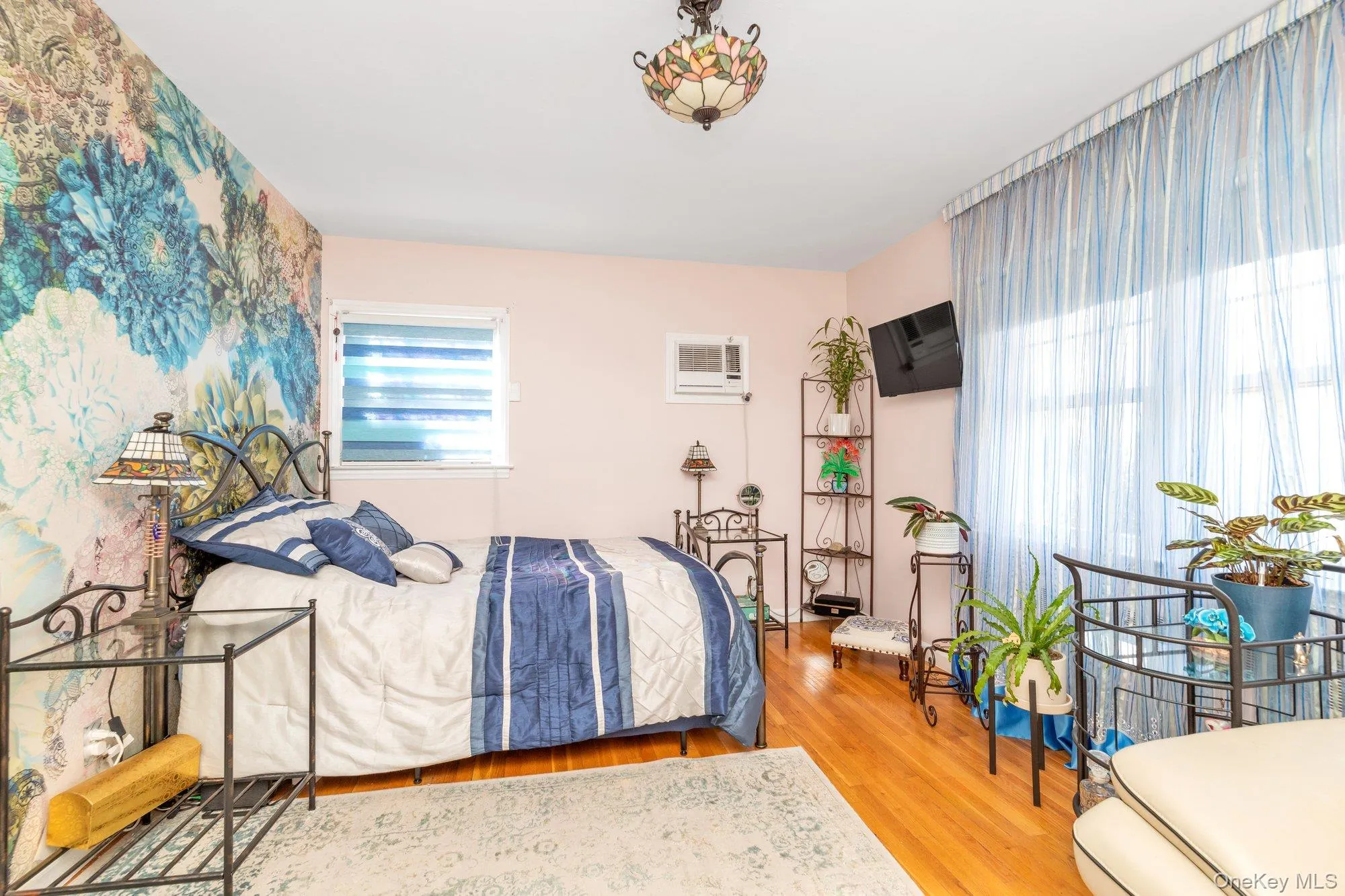 Bedroom featuring wood finished floors and a wall unit AC Bedroom featuring wood finished floors and a wall unit AC