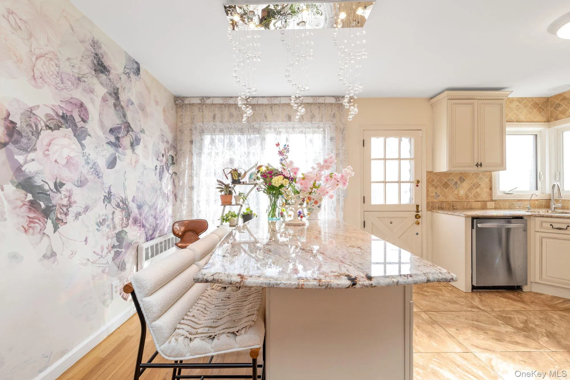 Kitchen featuring cream cabinetry, light stone counters, dishwasher, backsplash, and a kitchen bar Kitchen featuring cream cabinetry, light stone counters, dishwasher, backsplash, and a kitchen bar
