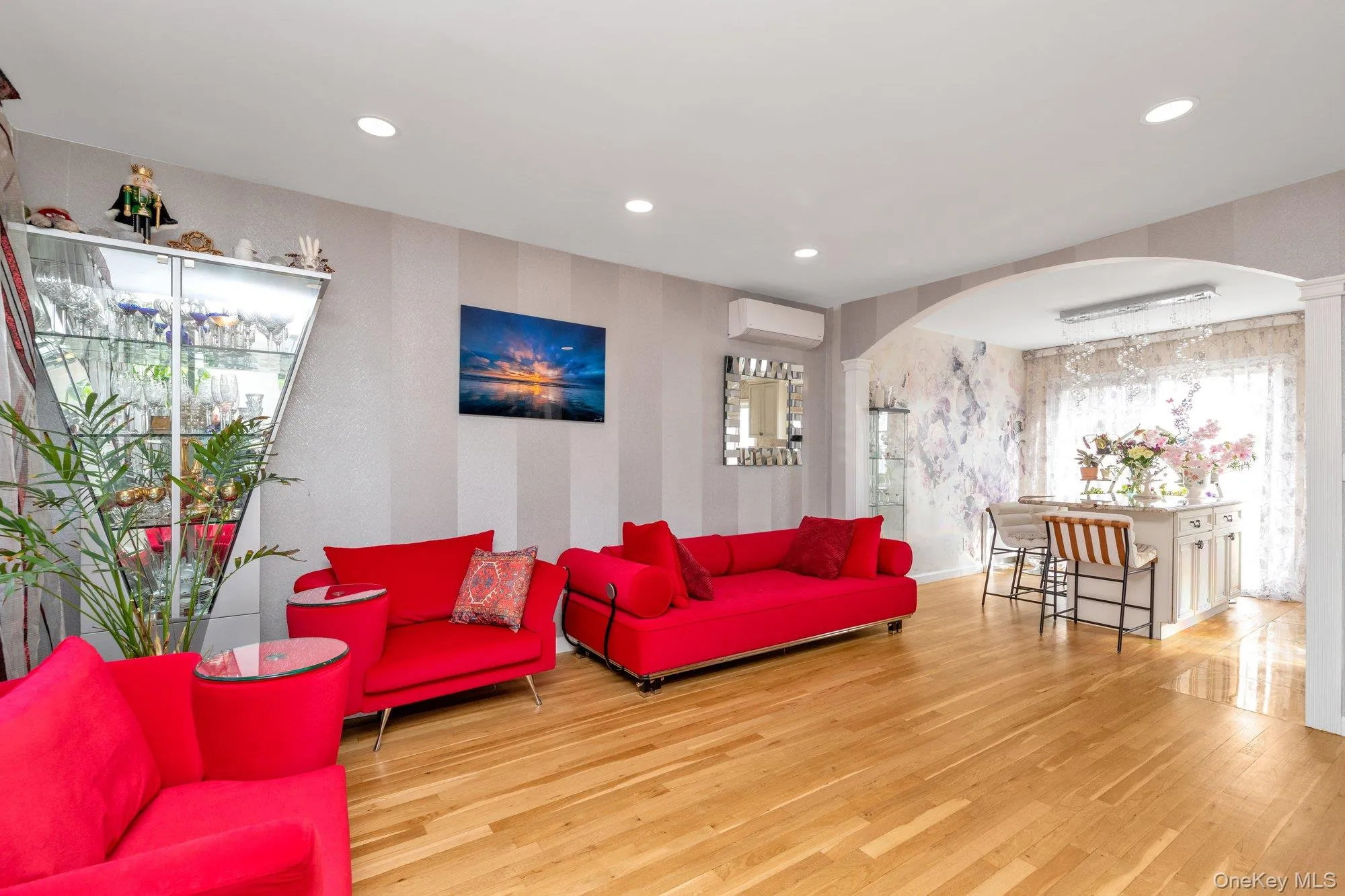 Living room with light wood-type flooring, wallpapered walls, arched walkways, plenty of natural light, and recessed lighting Living room with light wood-type flooring, wallpapered walls, arched walkways, plenty of natural light, and recessed lighting