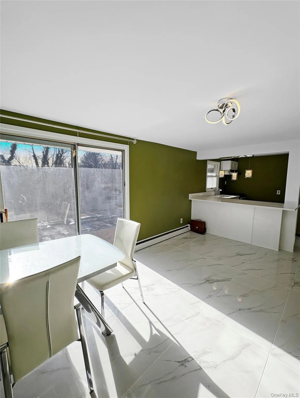 Dining area with light marble finish floors and a baseboard radiator Dining area with light marble finish floors and a baseboard radiator