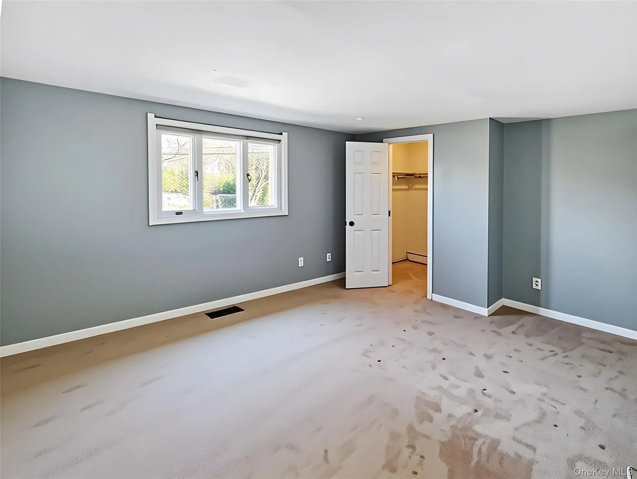Unfurnished bedroom with a spacious closet, a baseboard heating unit, and light colored carpet Unfurnished bedroom with a spacious closet, a baseboard heating unit, and light colored carpet