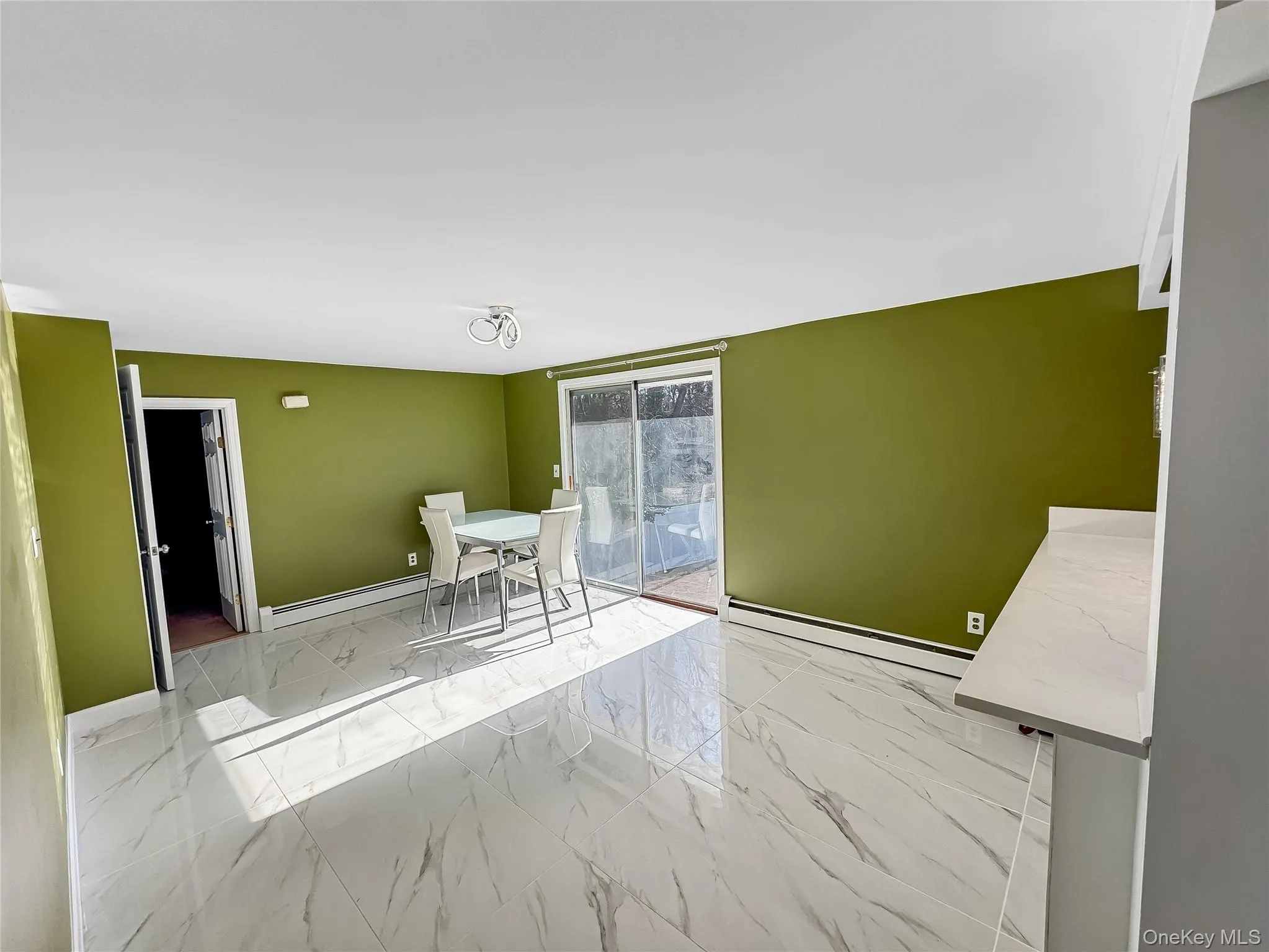 Unfurnished dining area featuring light marble finish flooring and baseboard heating Unfurnished dining area featuring light marble finish flooring and baseboard heating