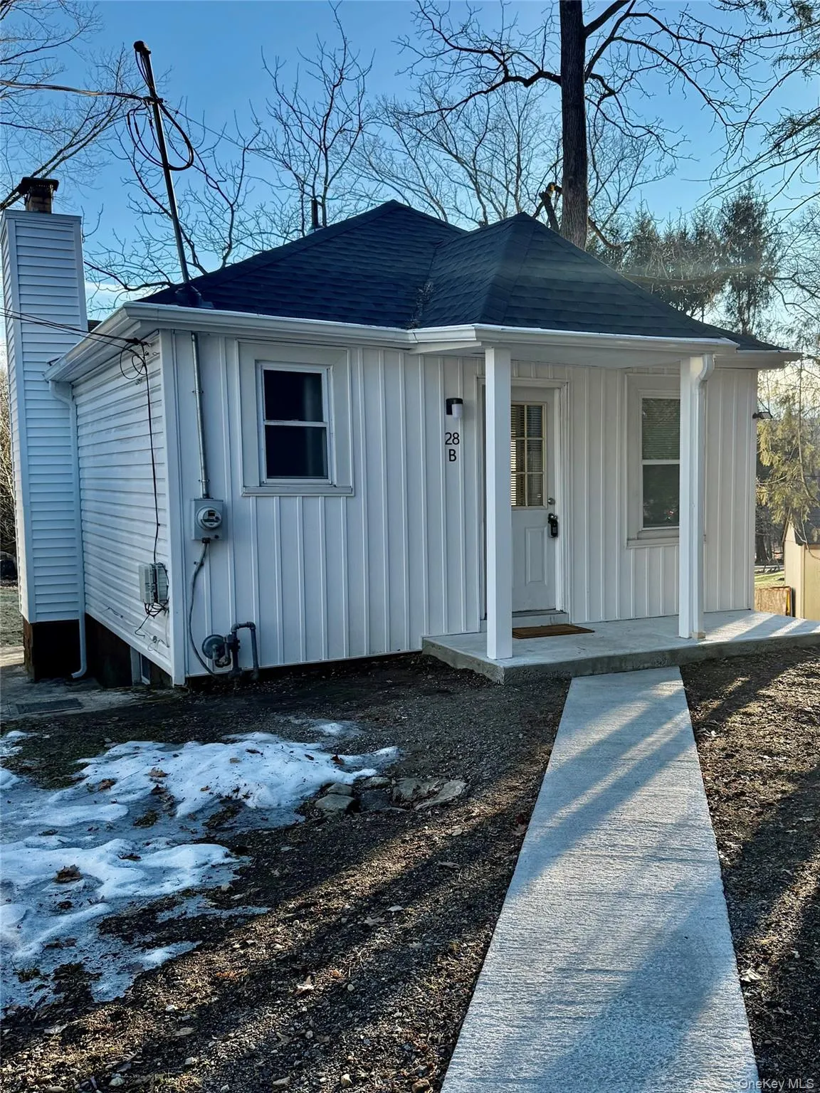 View of front facade with board and batten siding, covered porch, a chimney, and a shingled roof View of front facade with board and batten siding, covered porch, a chimney, and a shingled roof