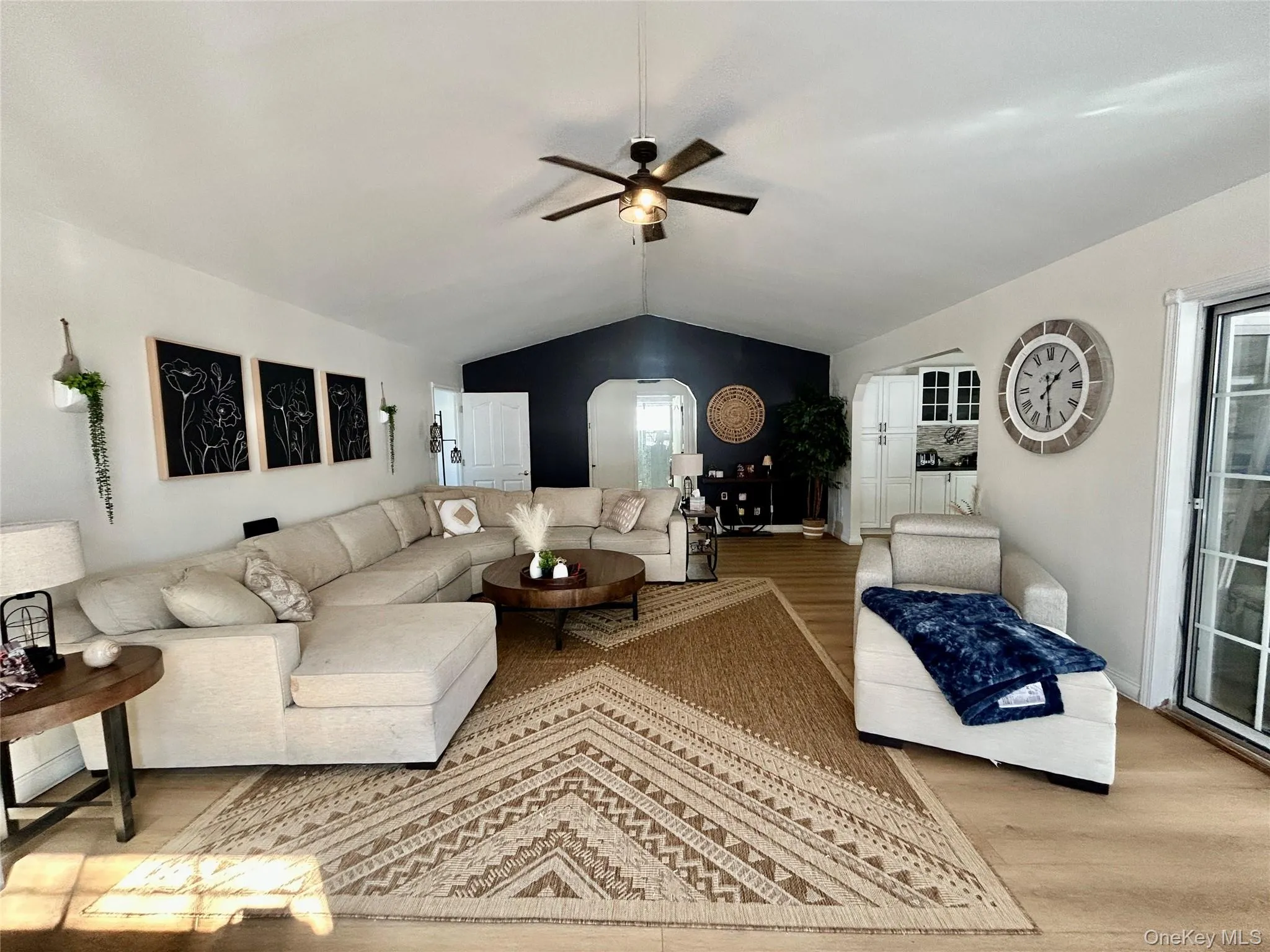 Living room featuring arched walkways, ceiling fan, and wood finished floors Living room featuring arched walkways, ceiling fan, and wood finished floors