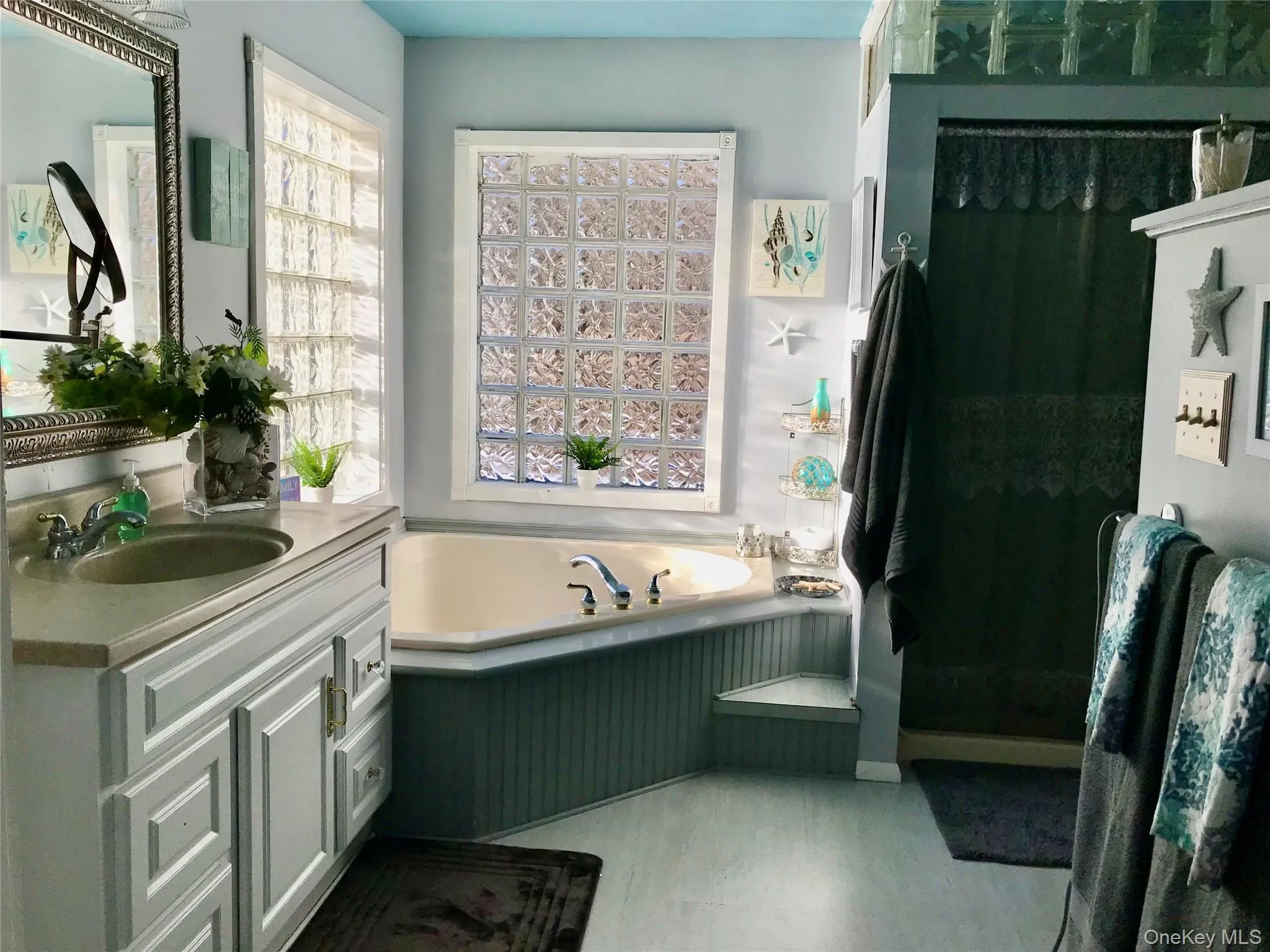 Full bath with a garden tub, vanity, and light wood-type flooring Full bath with a garden tub, vanity, and light wood-type flooring