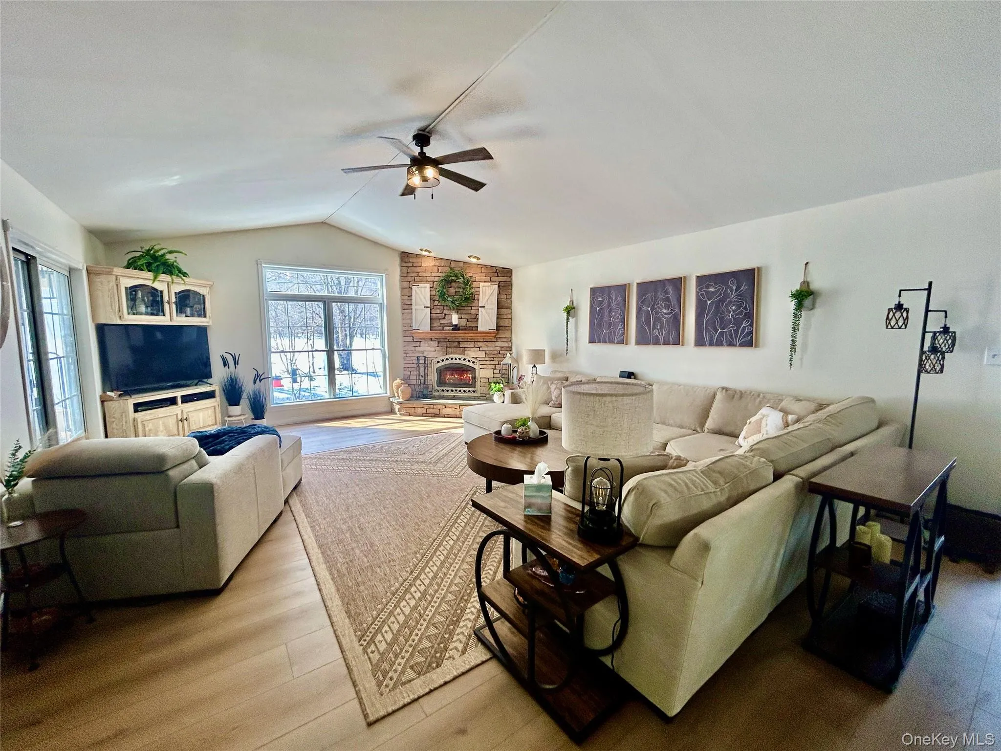 Living room featuring wood finished floors, a fireplace, and ceiling fan Living room featuring wood finished floors, a fireplace, and ceiling fan