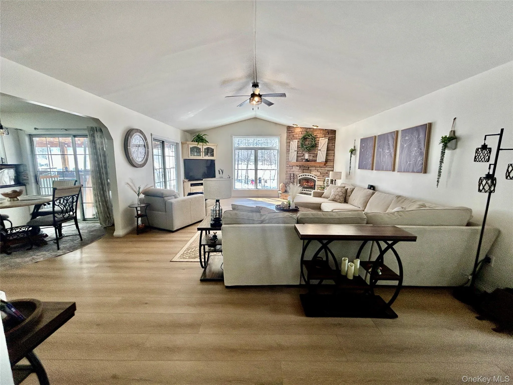 Living room with wood finished floors, ceiling fan, arched walkways, and a fireplace Living room with wood finished floors, ceiling fan, arched walkways, and a fireplace