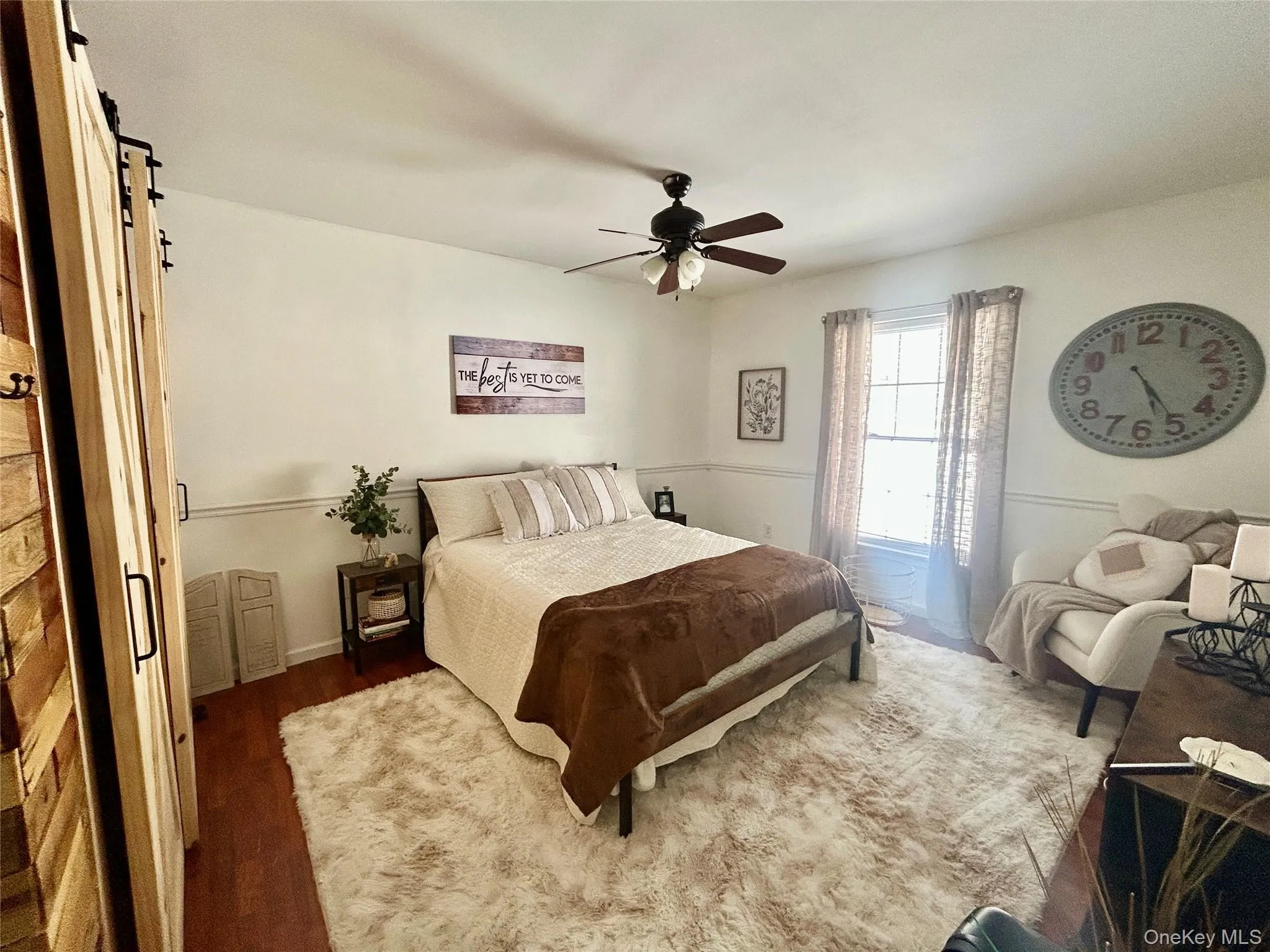 Bedroom featuring a barn door, dark wood finished floors, and a ceiling fan Bedroom featuring a barn door, dark wood finished floors, and a ceiling fan
