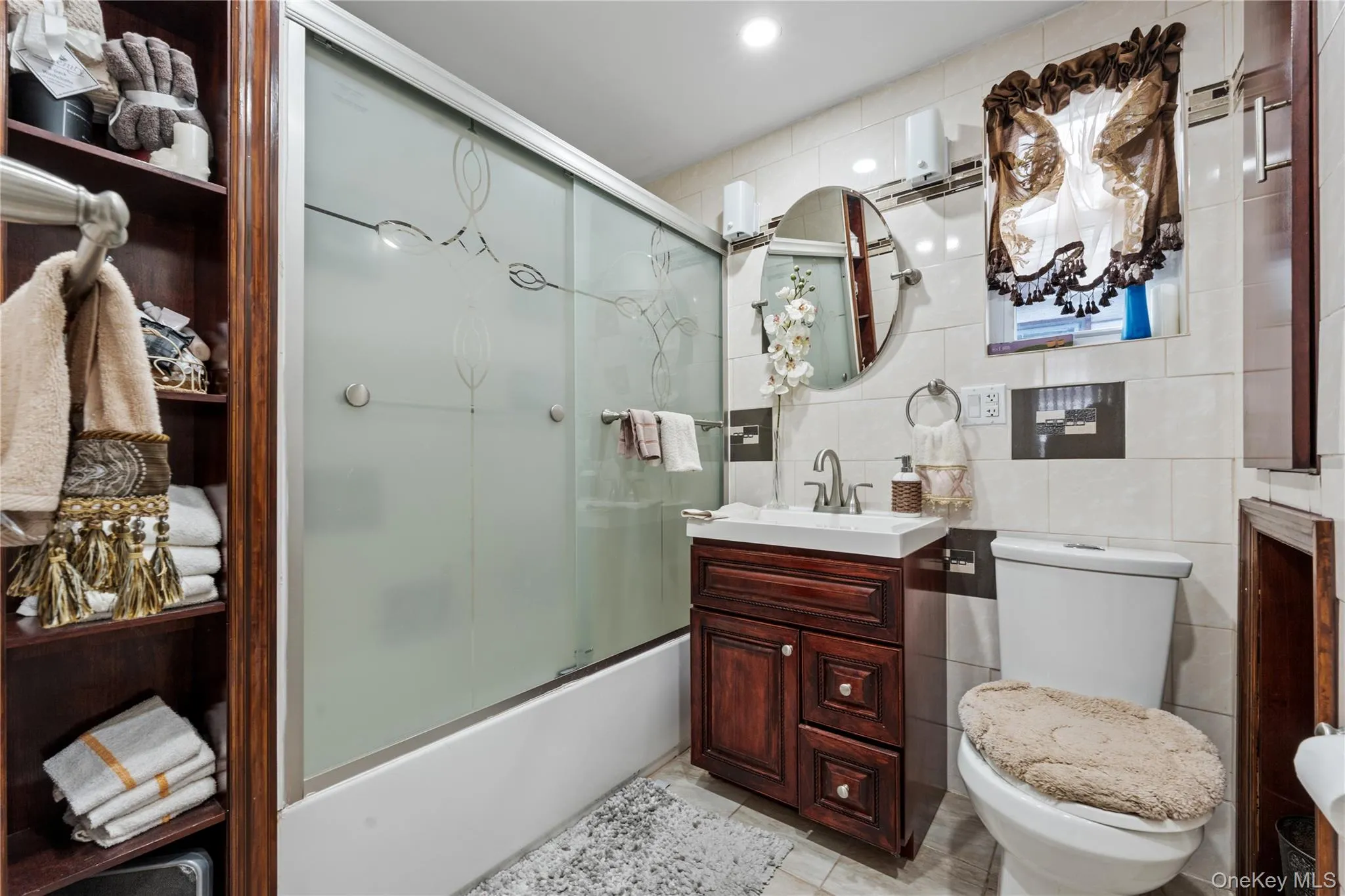 Full bath featuring tile walls, enclosed tub / shower combo, and vanity Full bath featuring tile walls, enclosed tub / shower combo, and vanity