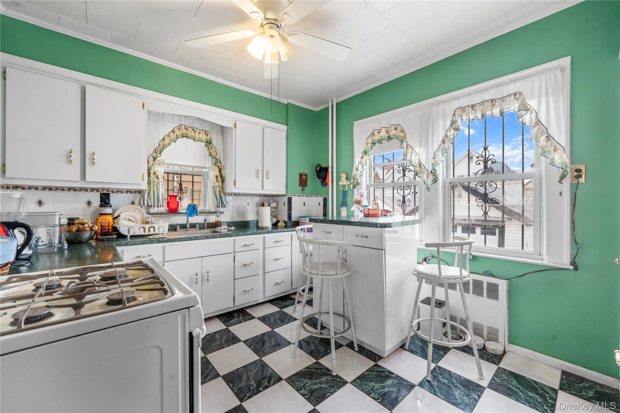 Kitchen with white range with gas stovetop, white cabinets, dark flooring, dark countertops, and crown molding Kitchen with white range with gas stovetop, white cabinets, dark flooring, dark countertops, and crown molding