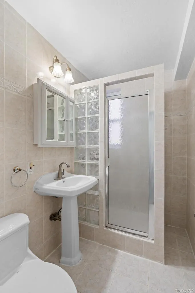 Bathroom with tile walls, a stall shower, and light tile patterned flooring Bathroom with tile walls, a stall shower, and light tile patterned flooring