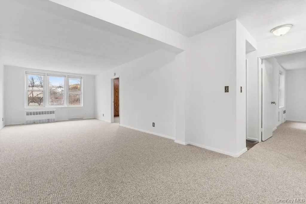 Unfurnished room with light carpet and radiator heating unit Unfurnished room with light carpet and radiator heating unit