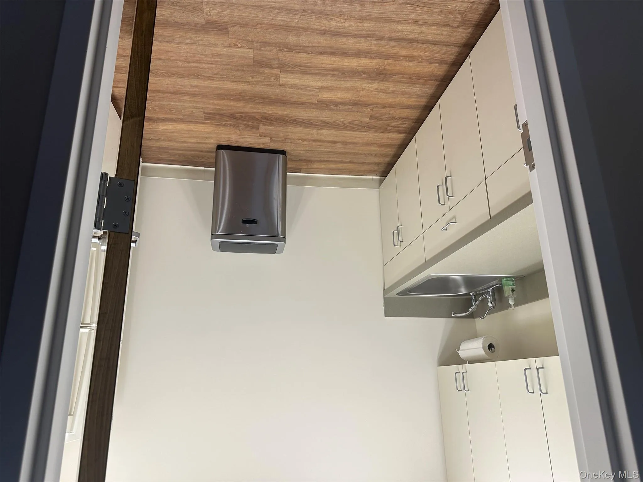 Kitchen featuring white cabinets, dark wood-style flooring, and light countertops Kitchen featuring white cabinets, dark wood-style flooring, and light countertops