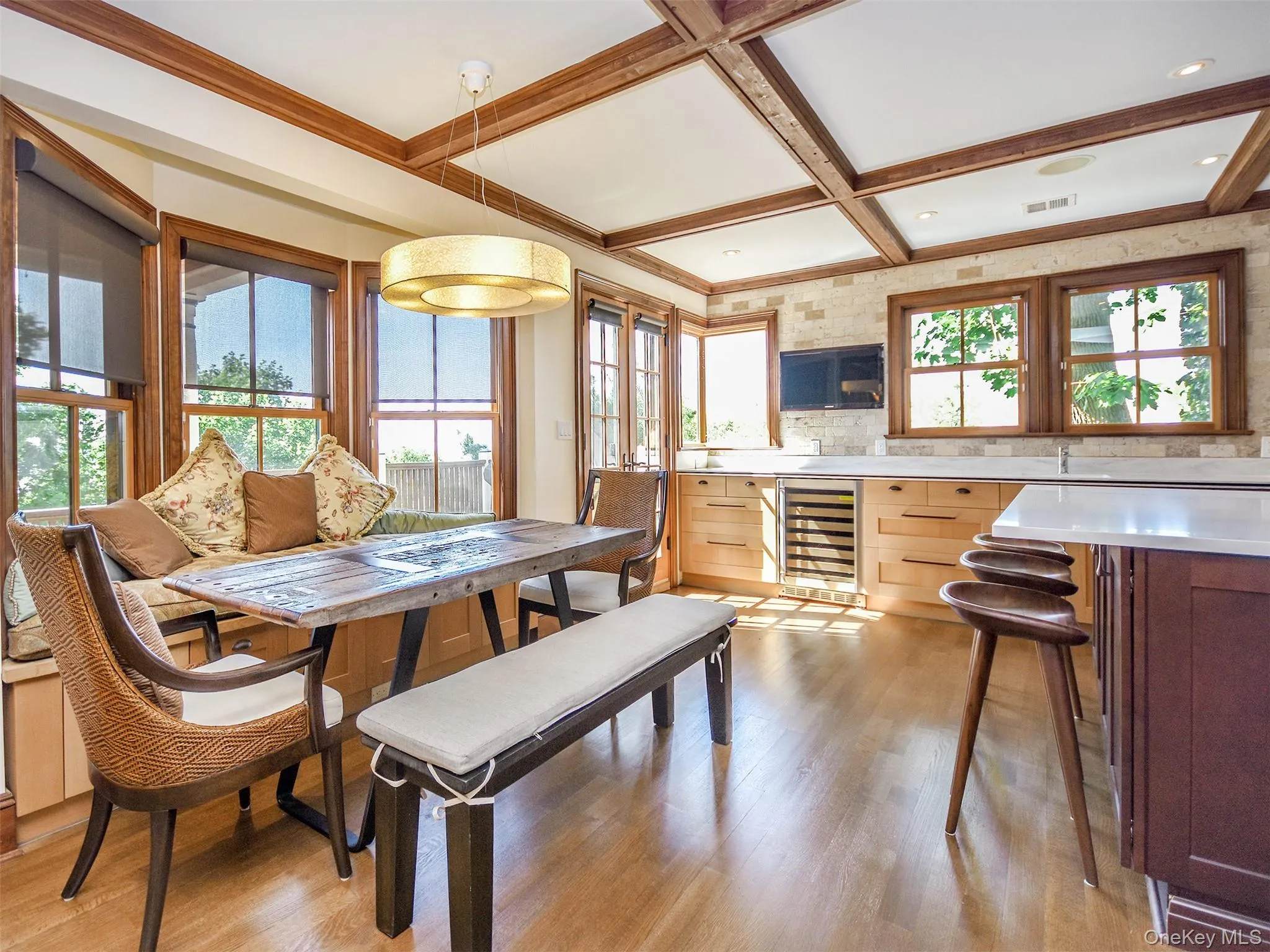 Dining area featuring beverage/wine cooler, light wood-type flooring, coffered ceiling, and beamed ceiling Dining area featuring beverage/wine cooler, light wood-type flooring, coffered ceiling, and beamed ceiling