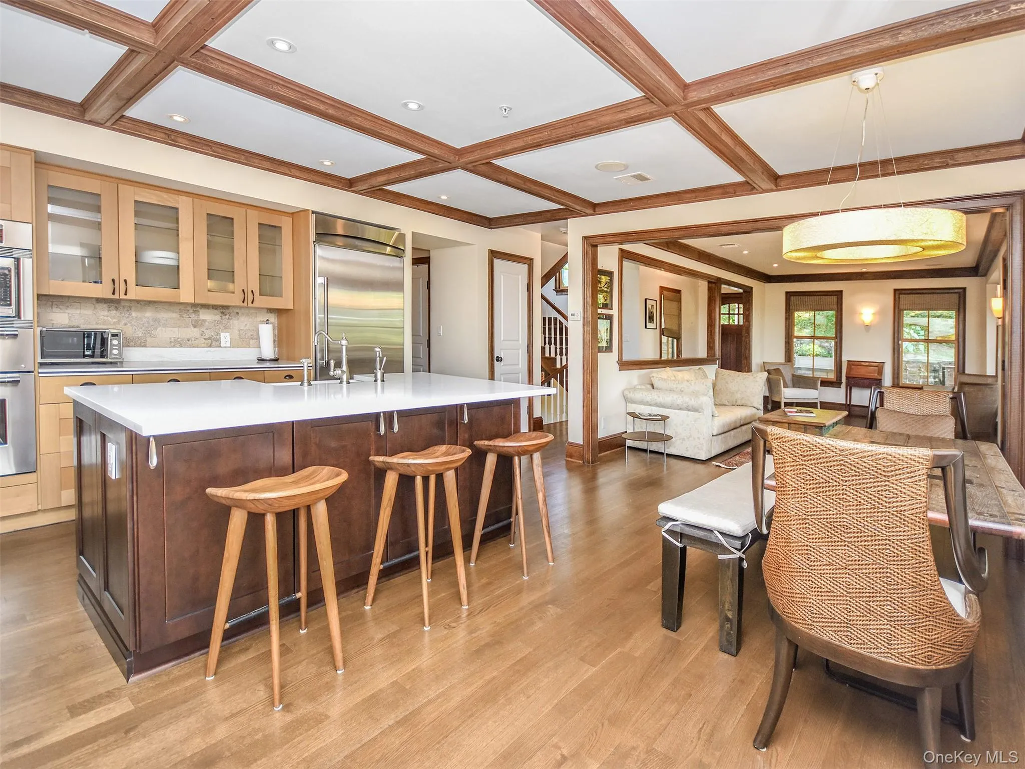 Kitchen with glass insert cabinets, a large island with sink, decorative light fixtures, a kitchen bar, and light wood-style flooring Kitchen with glass insert cabinets, a large island with sink, decorative light fixtures, a kitchen bar, and light wood-style flooring