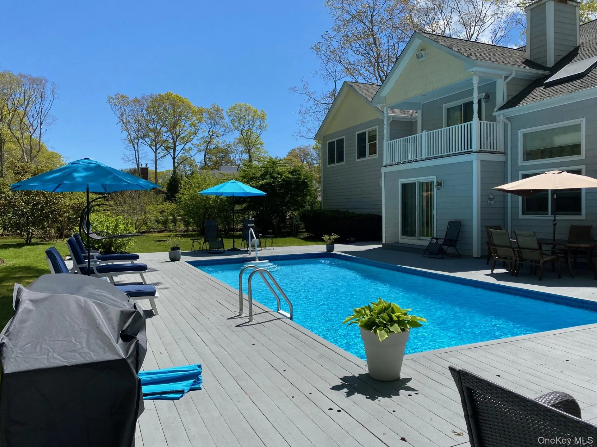 Swimming pool with a patio, outdoor dining space, a balcony, and a wooden deck Swimming pool with a patio, outdoor dining space, a balcony, and a wooden deck