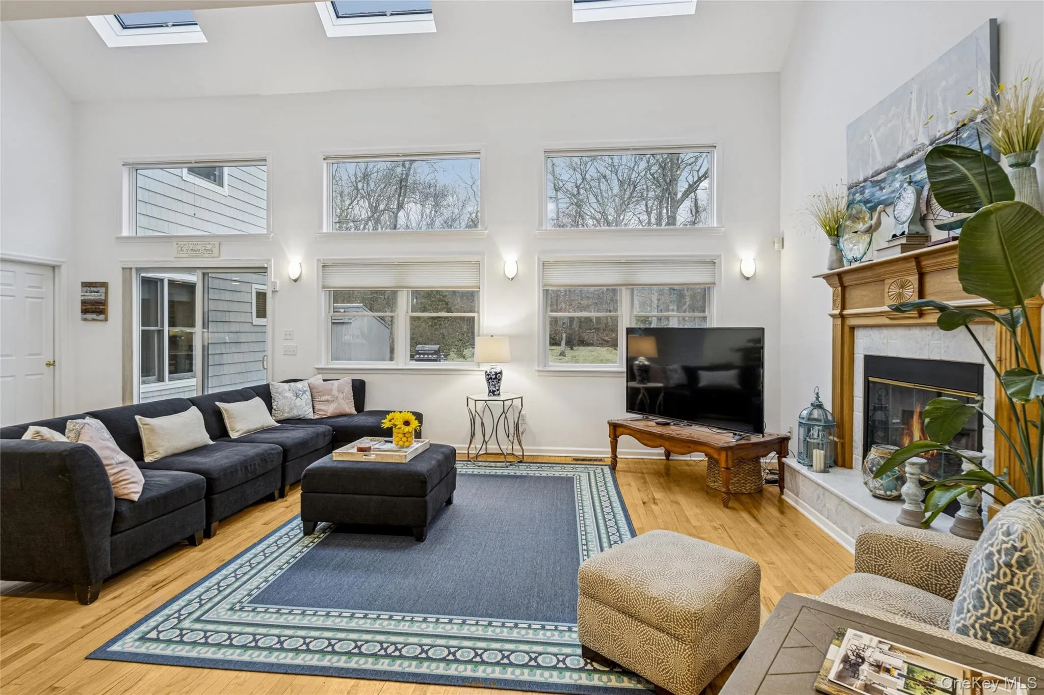 Living room with a towering ceiling, wood finished floors, and a high end fireplace Living room with a towering ceiling, wood finished floors, and a high end fireplace