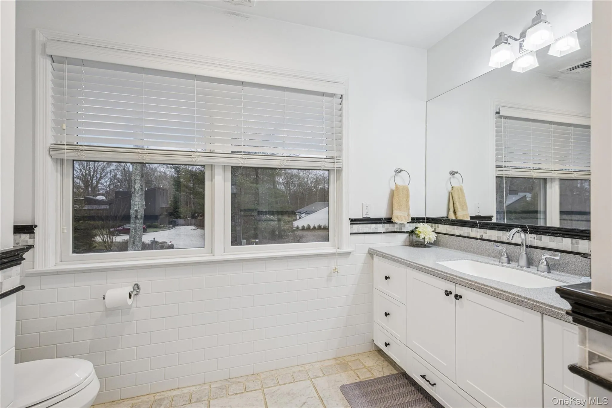Bathroom with tile walls, vanity, and wainscoting Bathroom with tile walls, vanity, and wainscoting