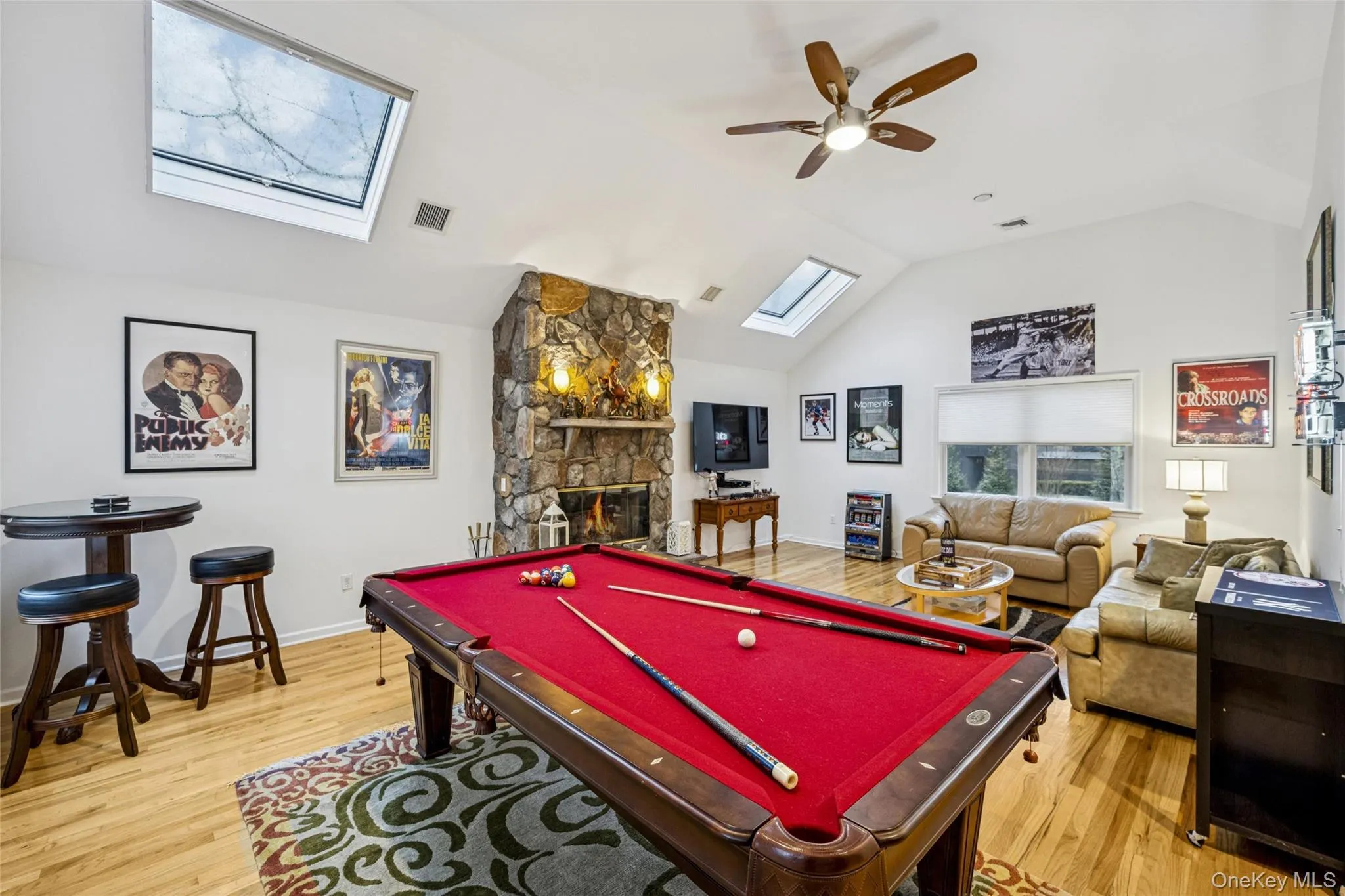 Recreation room with a skylight, lofted ceiling, billiards, a stone fireplace, and light wood finished floors Recreation room with a skylight, lofted ceiling, billiards, a stone fireplace, and light wood finished floors