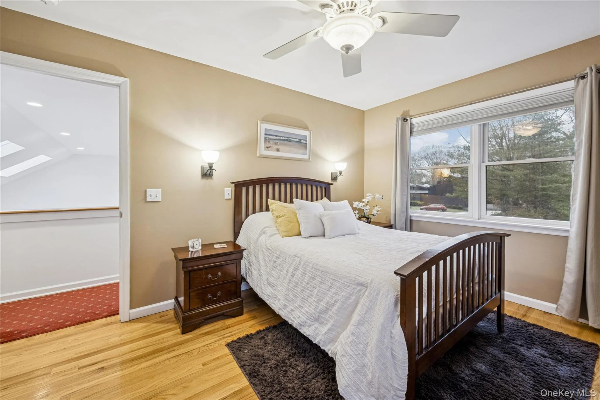Bedroom featuring light wood-style floors, a skylight, and ceiling fan Bedroom featuring light wood-style floors, a skylight, and ceiling fan