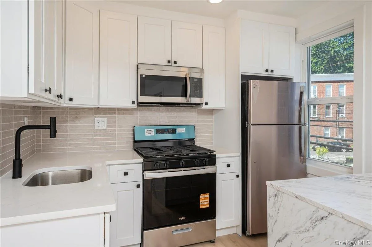 Kitchen featuring appliances with stainless steel finishes, white cabinetry, light stone counters, and recessed lighting Kitchen featuring appliances with stainless steel finishes, white cabinetry, light stone counters, and recessed lighting