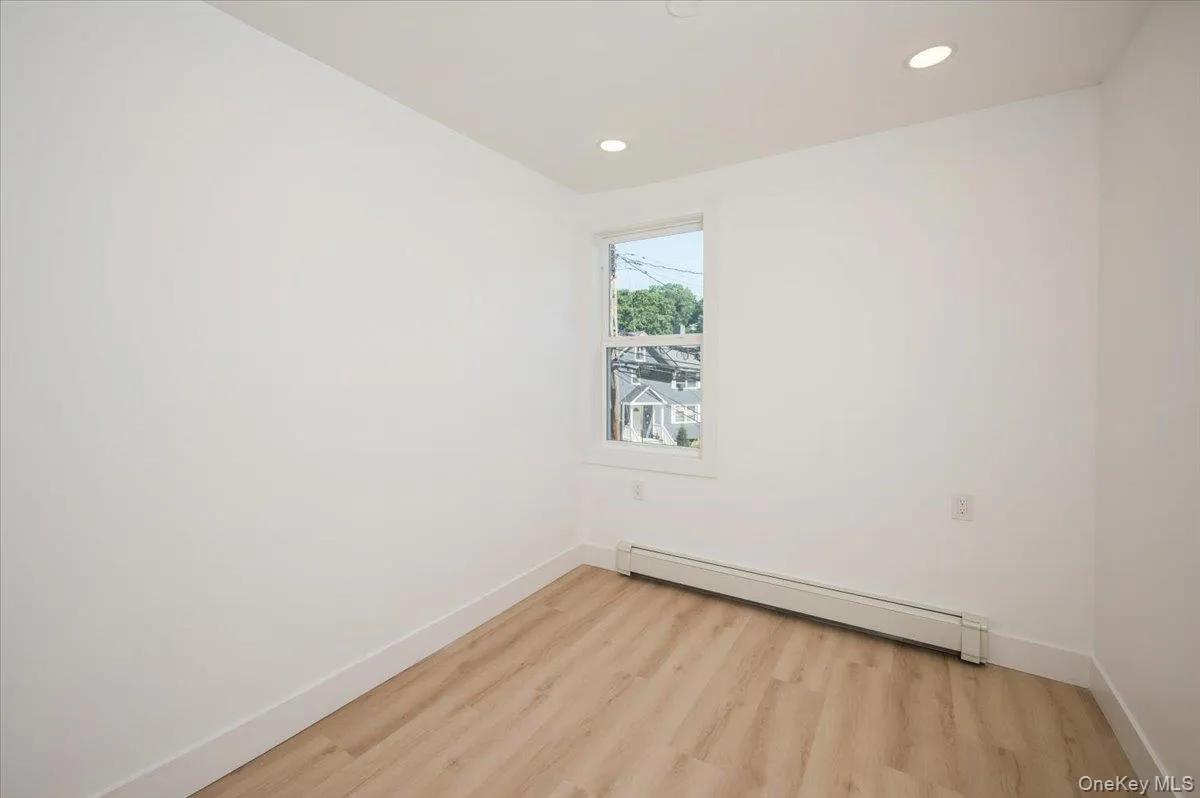 Empty room featuring baseboard heating, light wood finished floors, and recessed lighting Empty room featuring baseboard heating, light wood finished floors, and recessed lighting