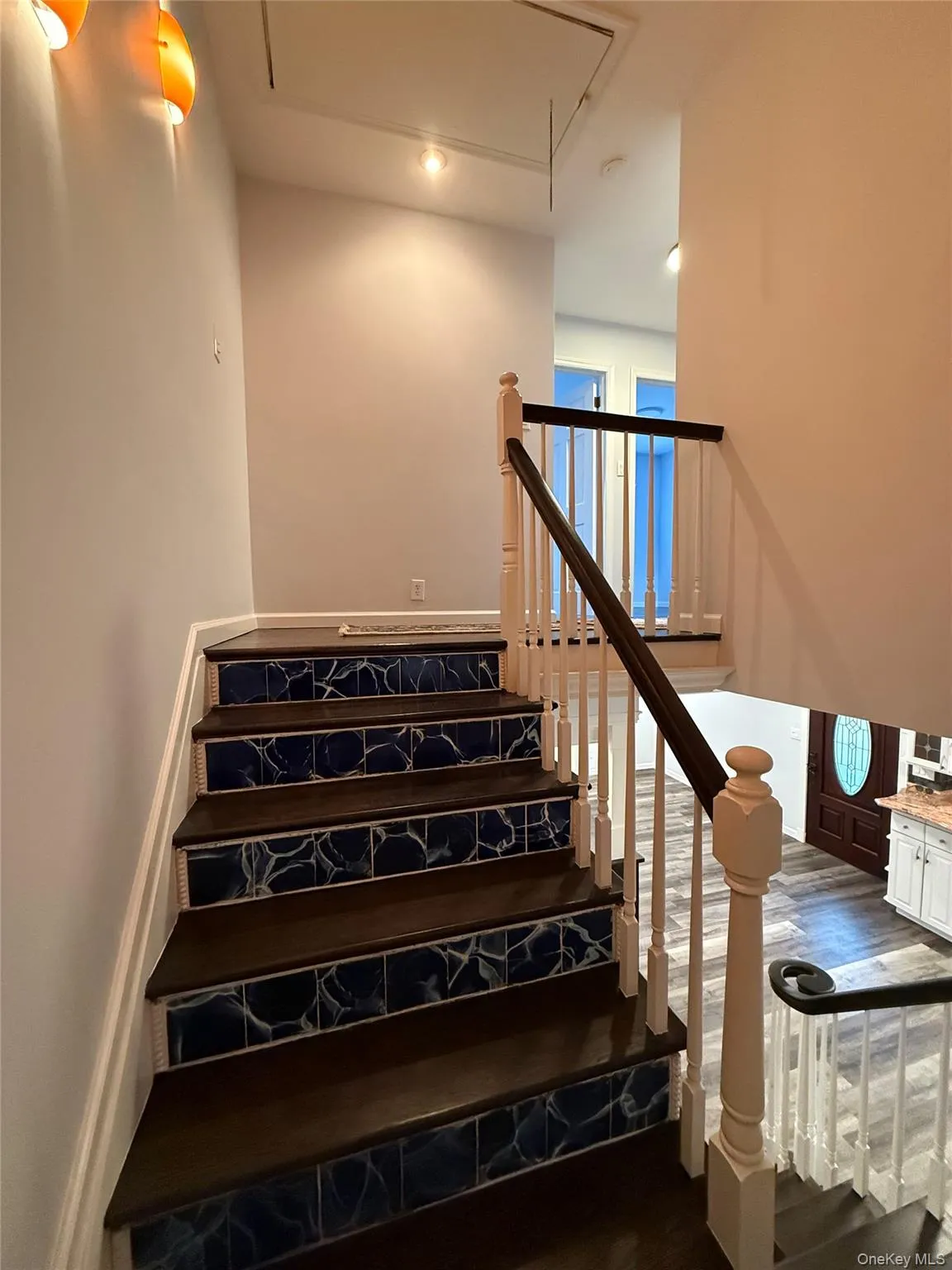 Staircase featuring attic access and wood finished floors Staircase featuring attic access and wood finished floors