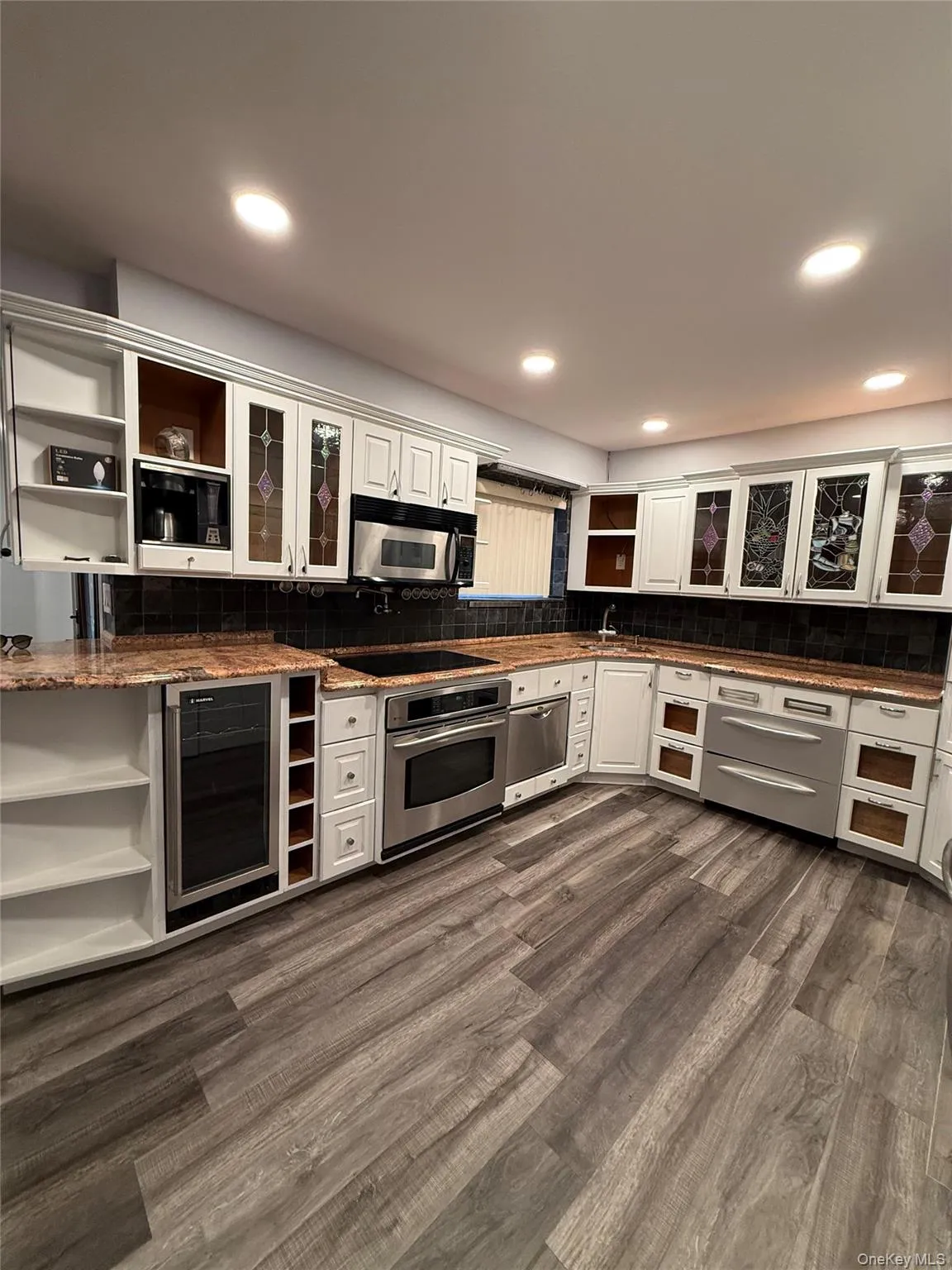 Kitchen with open shelves, white cabinetry, glass insert cabinets, wine cooler, and recessed lighting Kitchen with open shelves, white cabinetry, glass insert cabinets, wine cooler, and recessed lighting