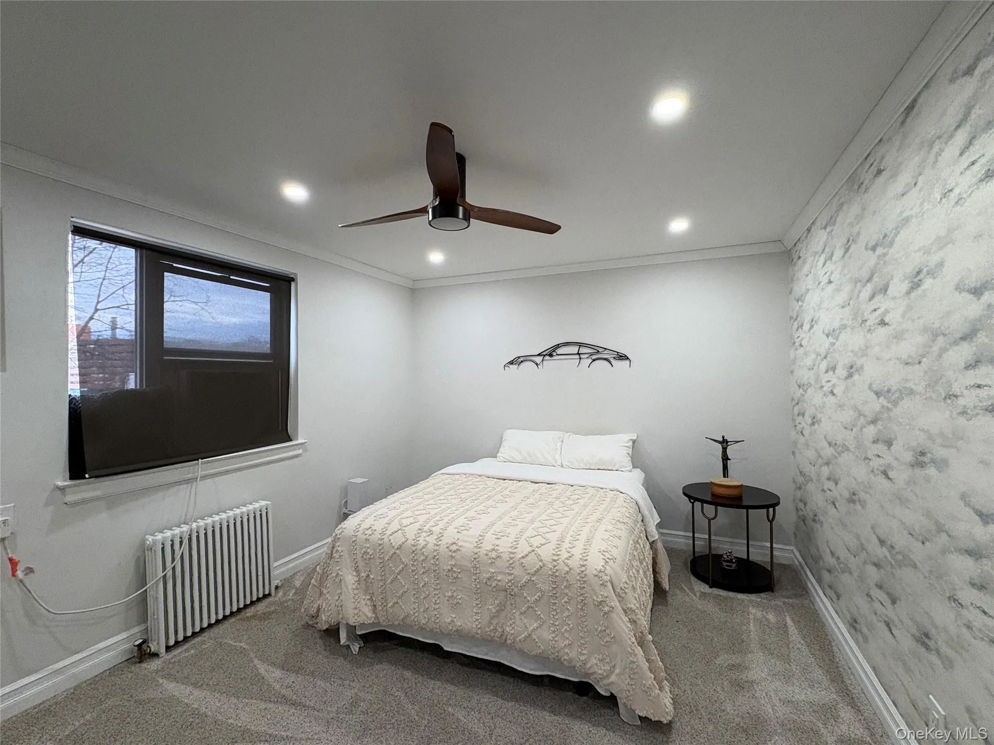 Carpeted bedroom with ornamental molding, radiator heating unit, ceiling fan, recessed lighting, and an accent wall Carpeted bedroom with ornamental molding, radiator heating unit, ceiling fan, recessed lighting, and an accent wall