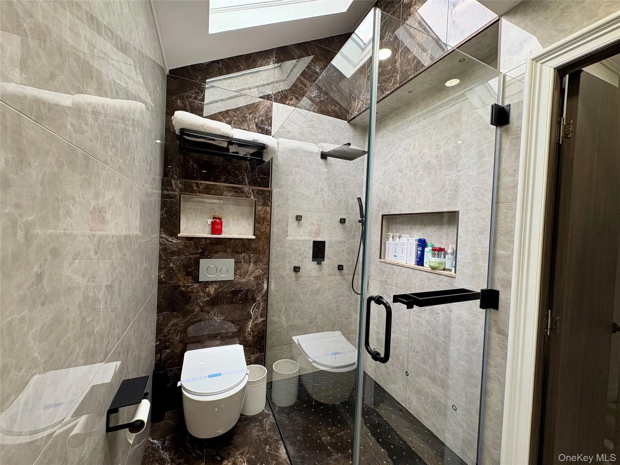Full bath with tile walls, a stall shower, and a skylight Full bath with tile walls, a stall shower, and a skylight