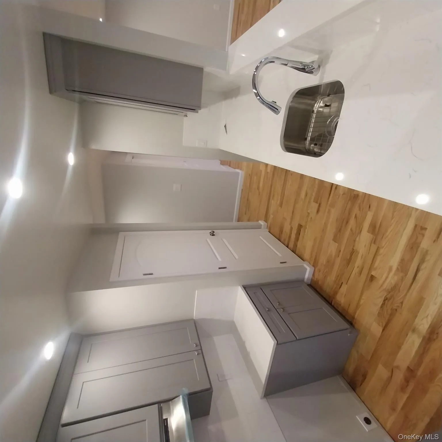 Kitchen featuring gray cabinetry, light wood finished floors, recessed lighting, light stone countertops, and range hood Kitchen featuring gray cabinetry, light wood finished floors, recessed lighting, light stone countertops, and range hood