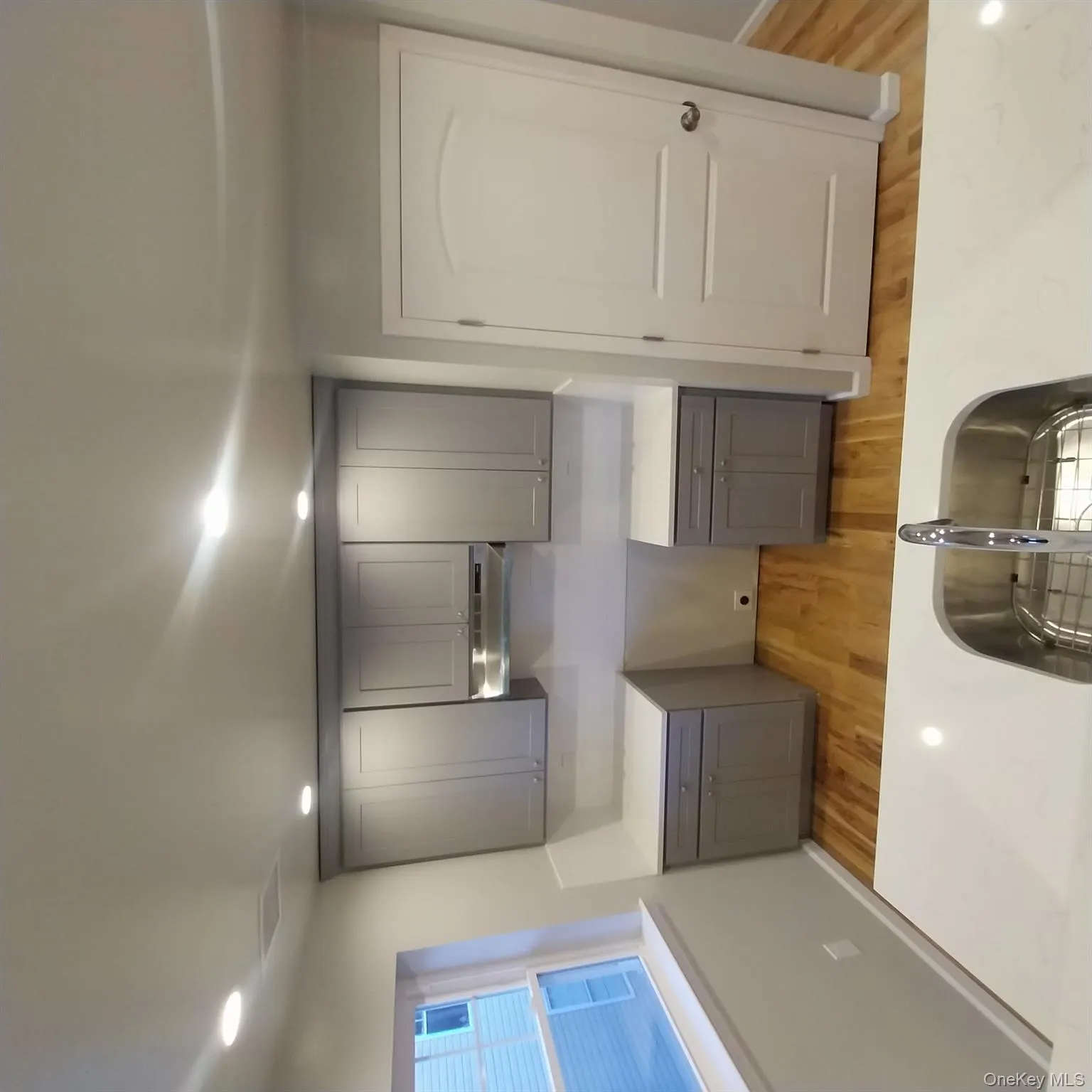 Kitchen with gray cabinets, light wood finished floors, range hood, and recessed lighting Kitchen with gray cabinets, light wood finished floors, range hood, and recessed lighting