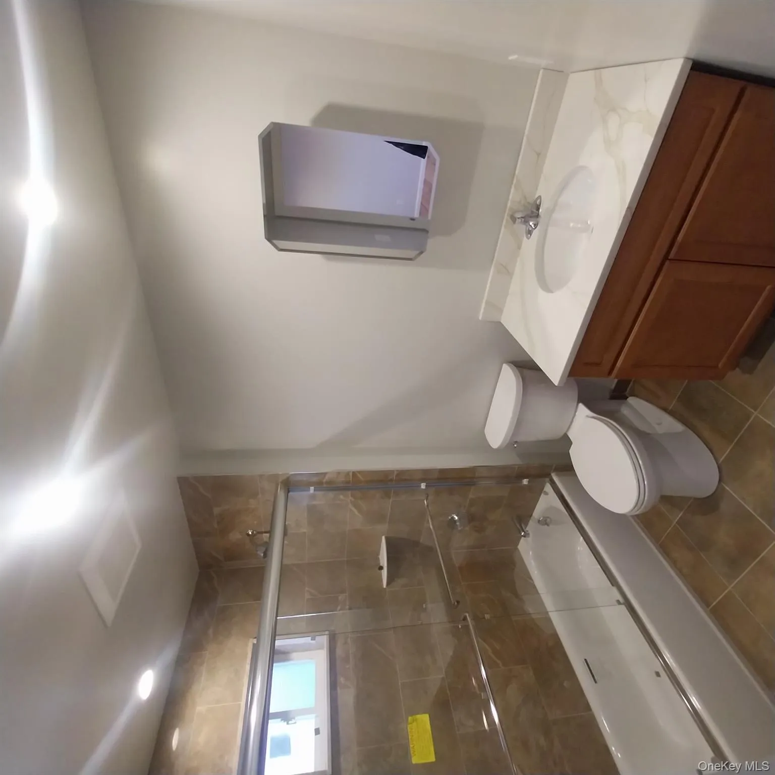 Full bathroom with bath / shower combo with glass door, vanity, and dark tile patterned flooring Full bathroom with bath / shower combo with glass door, vanity, and dark tile patterned flooring