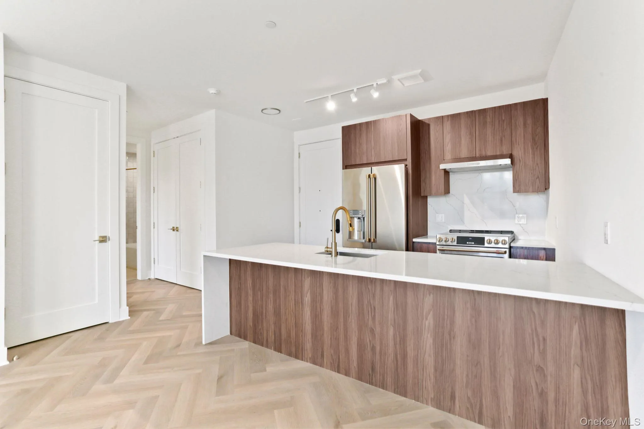 Kitchen with modern cabinets, light stone countertops, high end appliances, and a peninsula Kitchen with modern cabinets, light stone countertops, high end appliances, and a peninsula