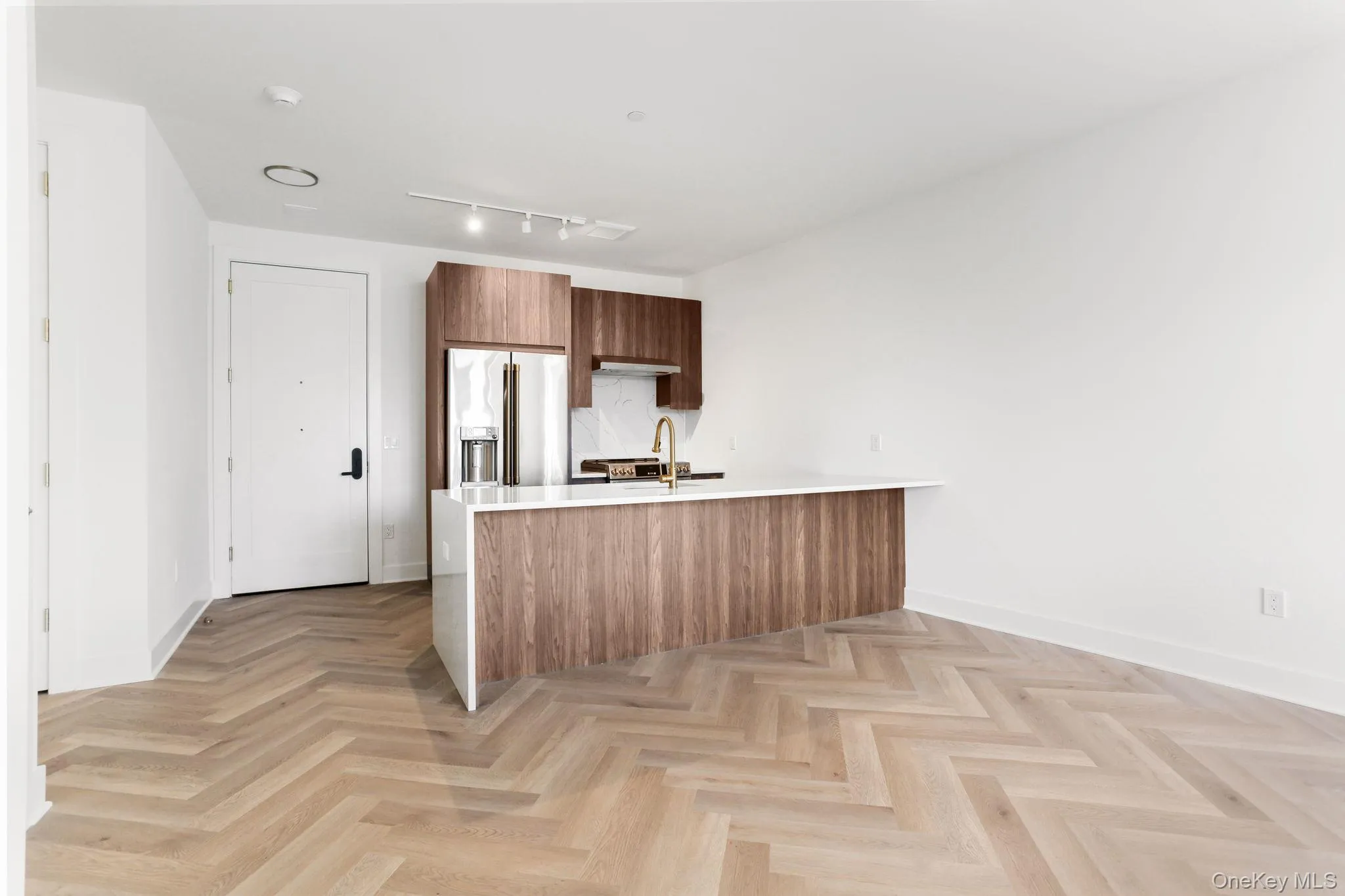 Kitchen featuring modern cabinets, a peninsula, brown cabinetry, light stone counters, and high quality fridge Kitchen featuring modern cabinets, a peninsula, brown cabinetry, light stone counters, and high quality fridge