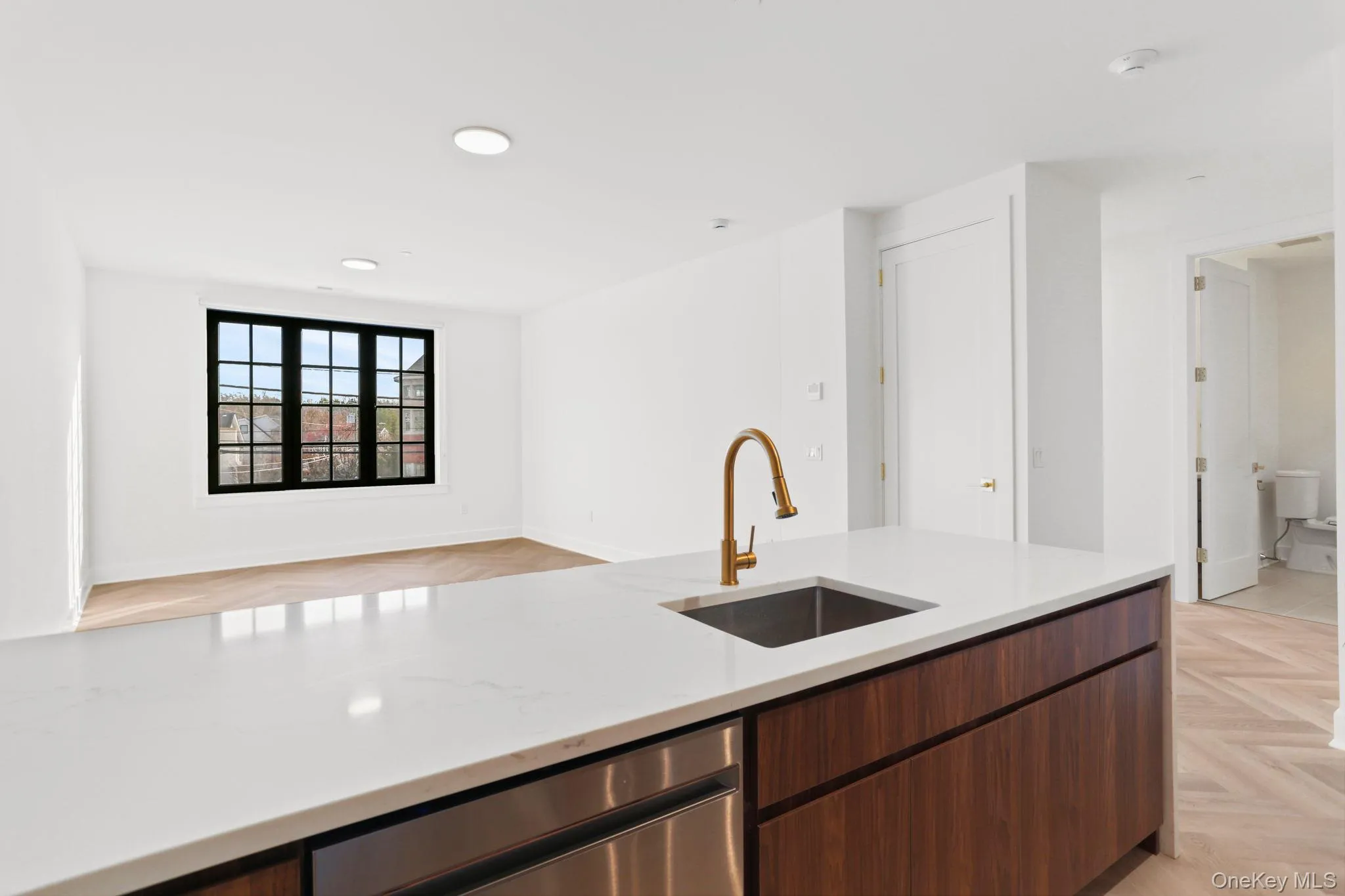 Kitchen featuring light stone countertops, dishwasher, open floor plan, modern cabinets, and dark brown cabinetry Kitchen featuring light stone countertops, dishwasher, open floor plan, modern cabinets, and dark brown cabinetry